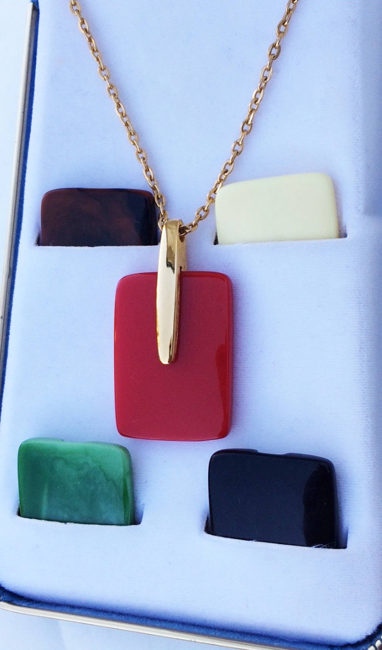 A fine and rare vintage Trifari Lucite pendant necklace box set. Authentic signed gilt metal item features five inter-changeable and secure-locking Lucite pendants. Unworn item retains original signature box. Pristine.