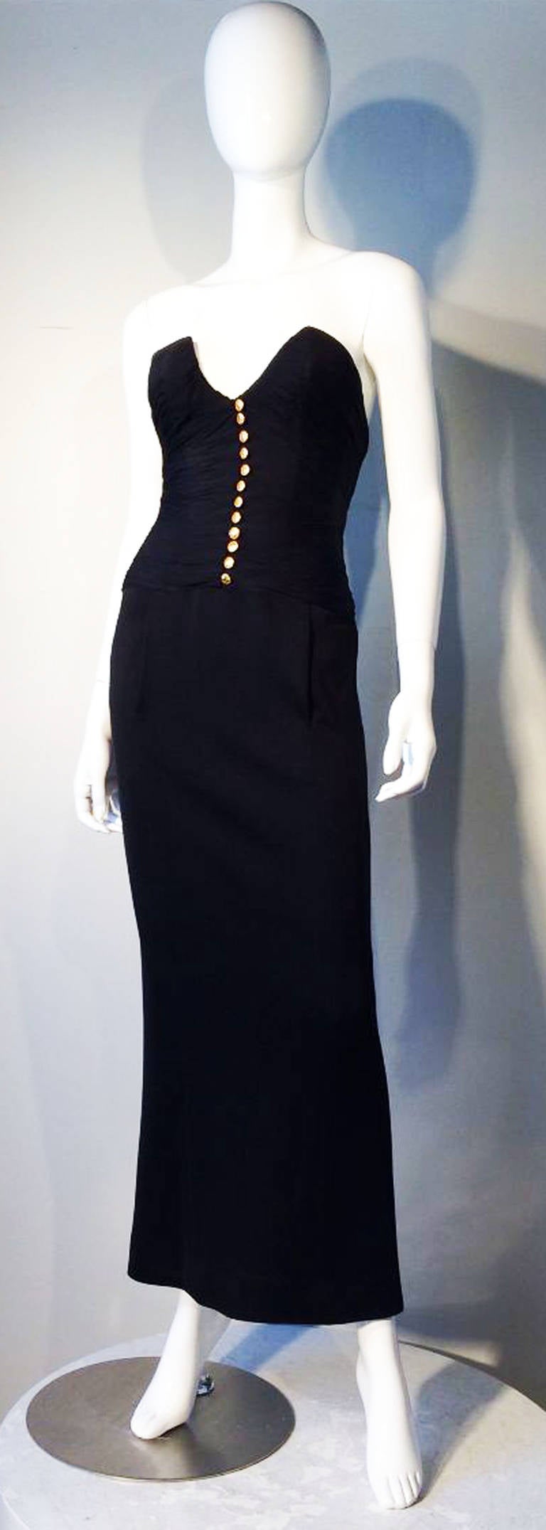 A fine and rare vintage Chanel strapless body conscience gown. Ruched silk chiffon bodice features decorative gilt logo buttons front center and matching jet black double knit floor length skirt. Item fully lined and zips up back. Pristine appears