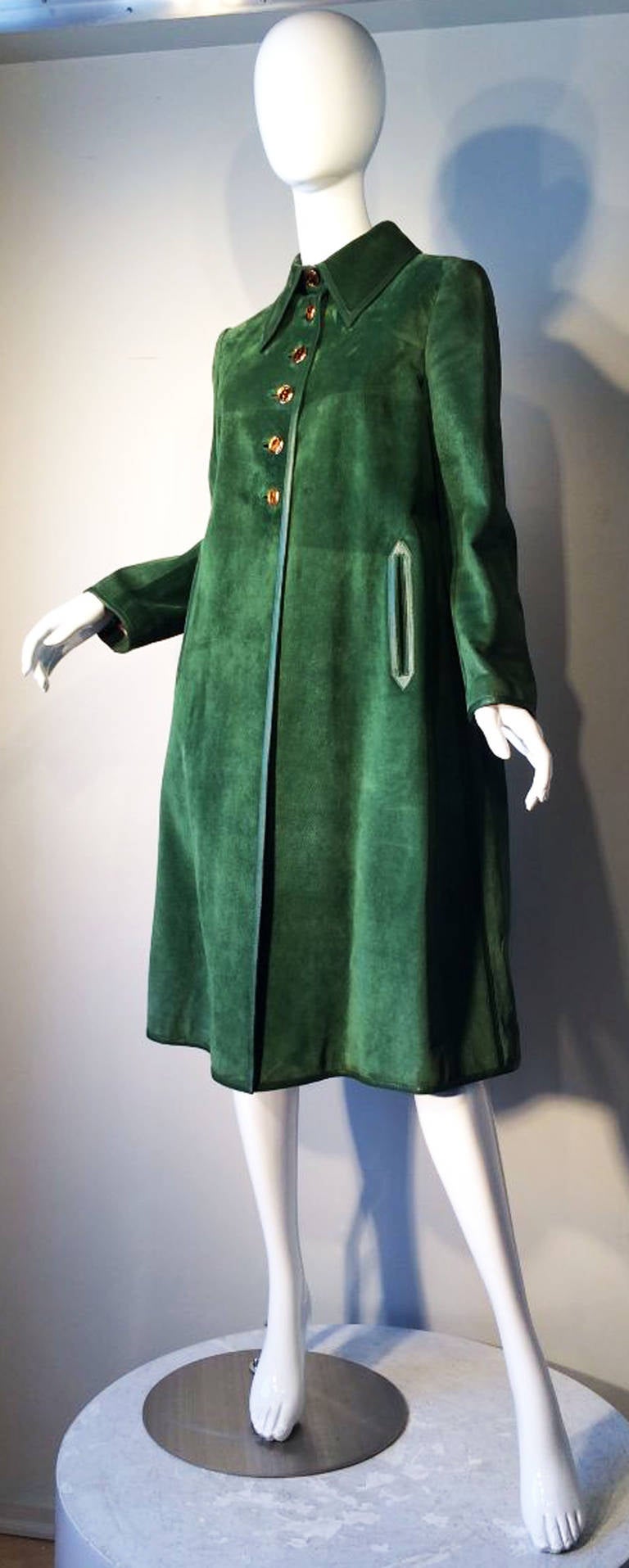 A fine and rare vintage Gucci suede leather swing coat. Vivid jade green suede item trimmed in matching green calf leather. Item fully silk lined and features inset pockets with a full swing hemline and iconic gilt and enamel logo buttons front.