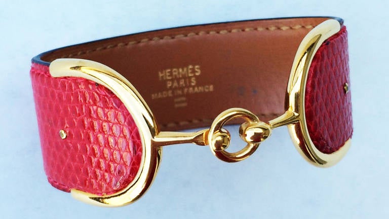 A fine and rare vintage Hermes yellow gold and reptile cuff bracelet. Authentic French hallmarks for 18K (marks date pre-1972). Bright red reptile skin exterior fully leather lined with mounted gold ends & center locking clasp. A rarely seen model