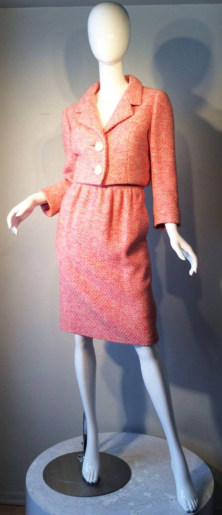 A fine and classic Norman Norell 2pc. day suit. Pink and ivory woven wool fabric item fully silk lined with button and zipper closures. Pristine appears unworn.