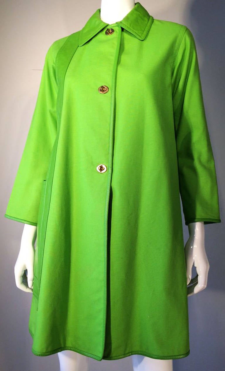A fine and rare vintage Bonnie Cashin leather trimmed canvas coat. Vivid lime green cotton canvas item trimmed in matching leather trim. Item features iconic brass turn lock closures and attached 