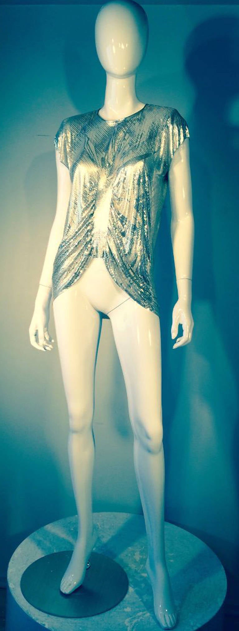 A fine, iconic and rare vintage Gianni Versace metal mesh tunic. Slinky hand abstract painted silver mesh item features a sculpted ruched bodice center plus matching metallic silver leather trim.  Attached shoulder pads and back zipper closure.