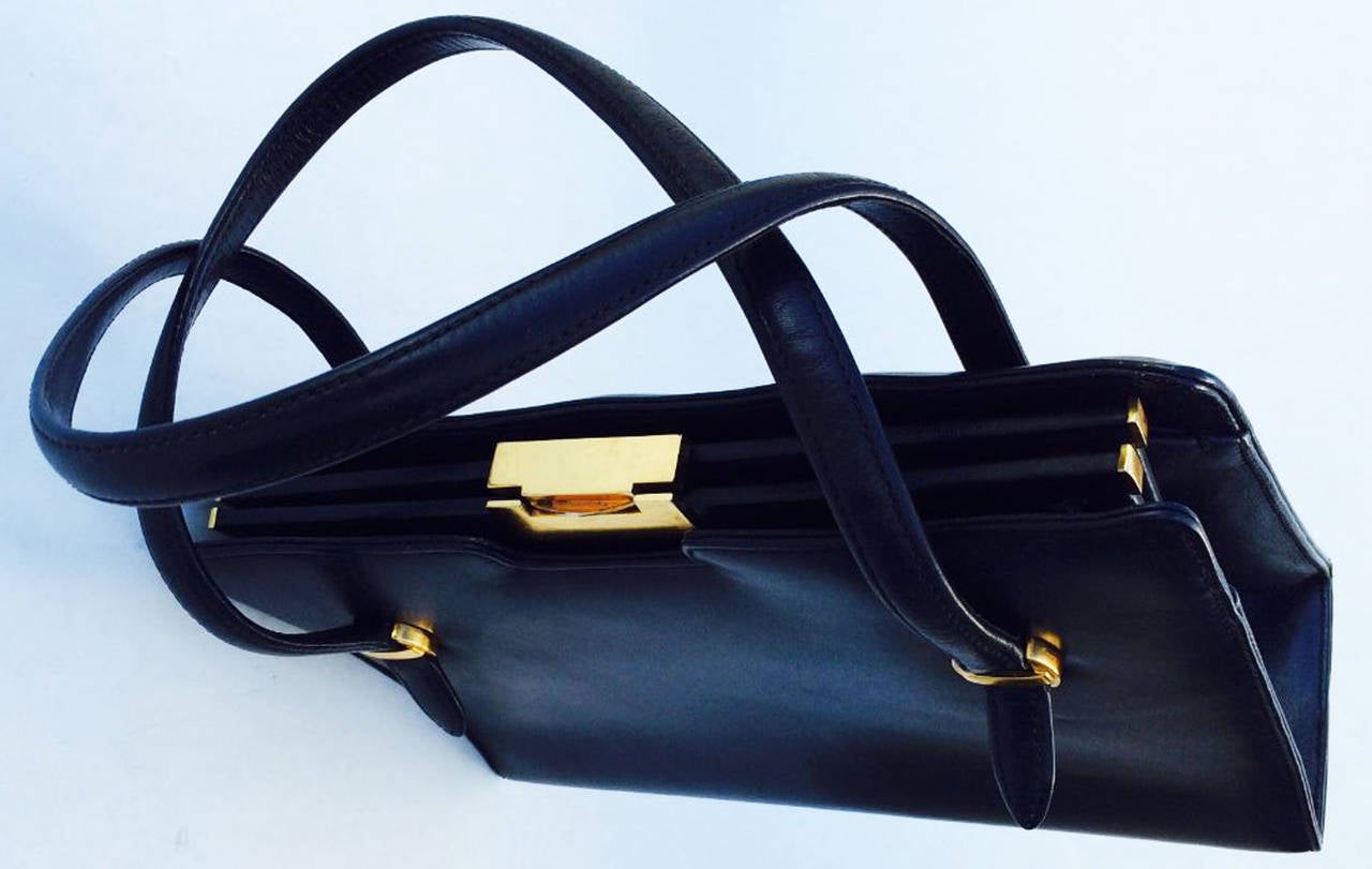 A fine vintage Gucci leather handbag. Fine black calf leather item features gilt clasp and hardware. Item fully lined in contrasting red calf leather. Bag measurements add a additional 5.5