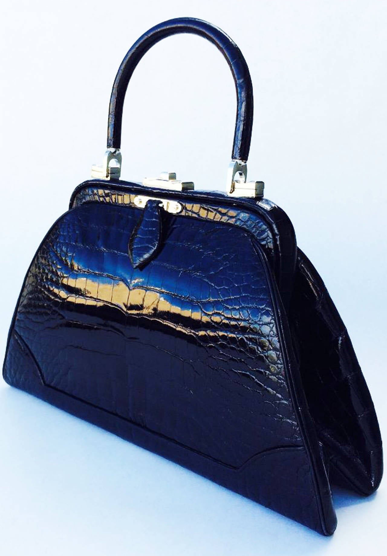 A exquisite and rare vintage Judith Leiber porosus crocodile handbag. Outstanding example features palladium plated hardware with a removable matching skins clutch handle. Item fully matching calf leather lined with original signature metal vanity