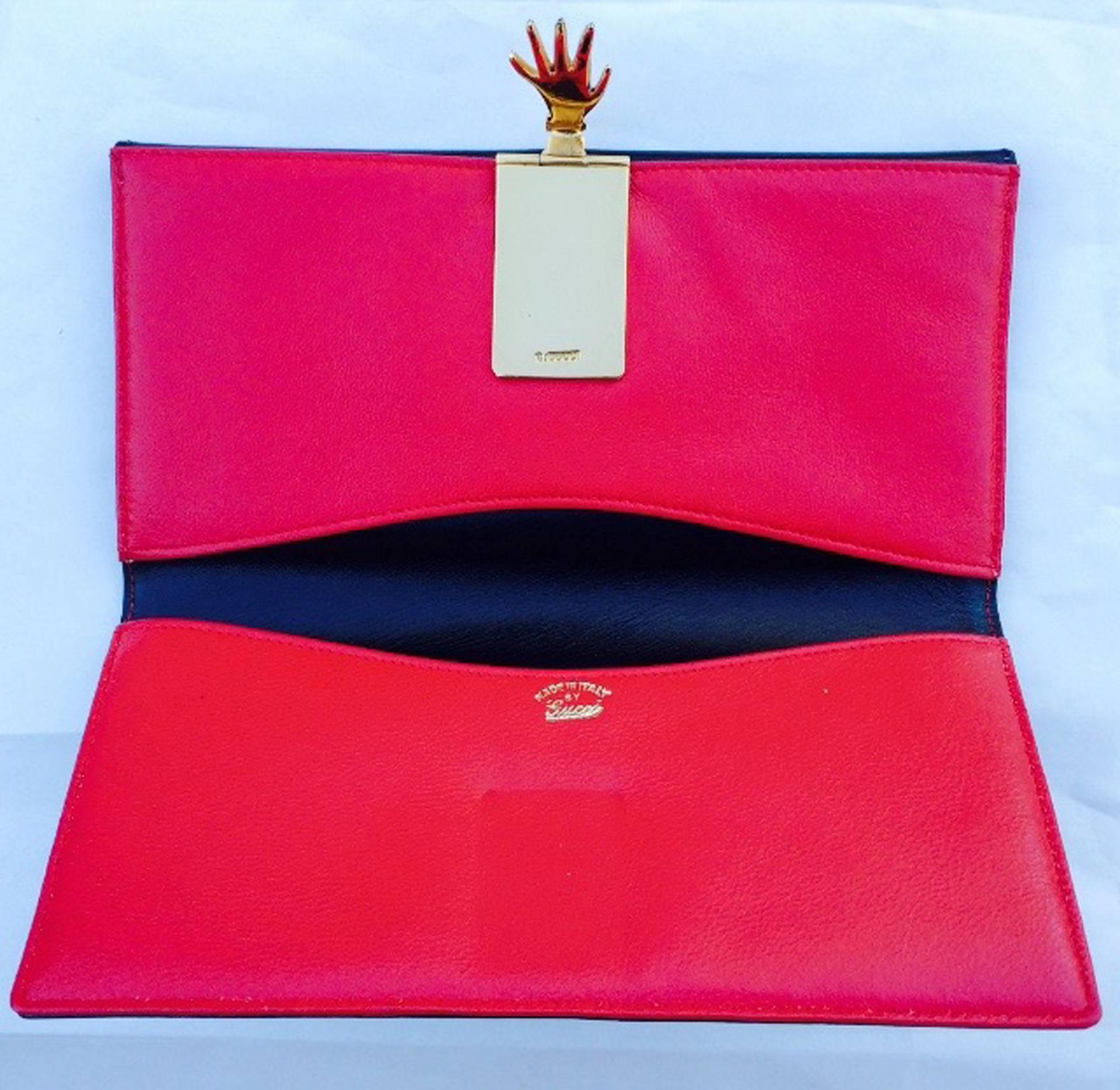 A fine vintage Gucci hand clutch wallet. Authentic calf leather item dyed a jet black exterior with a vivid red interior. Sculpted 