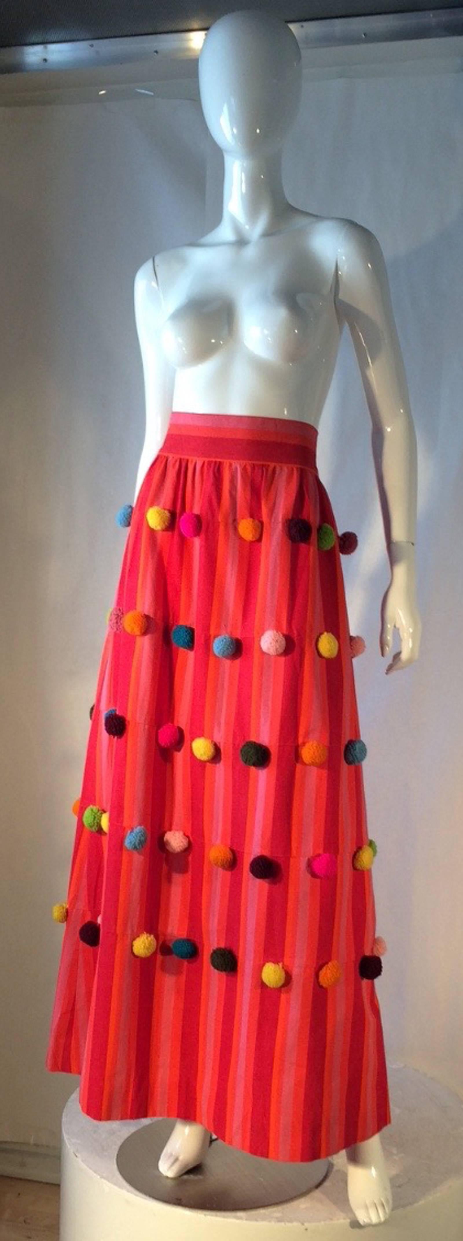 A fine and charming El Palomar maxi skirt. Authentic hand made Mexican pink/orange striped cotton item fully trimmed with multi-color pom poms. item. Item features a matching fabric waist band, original metal zipper. with a 68