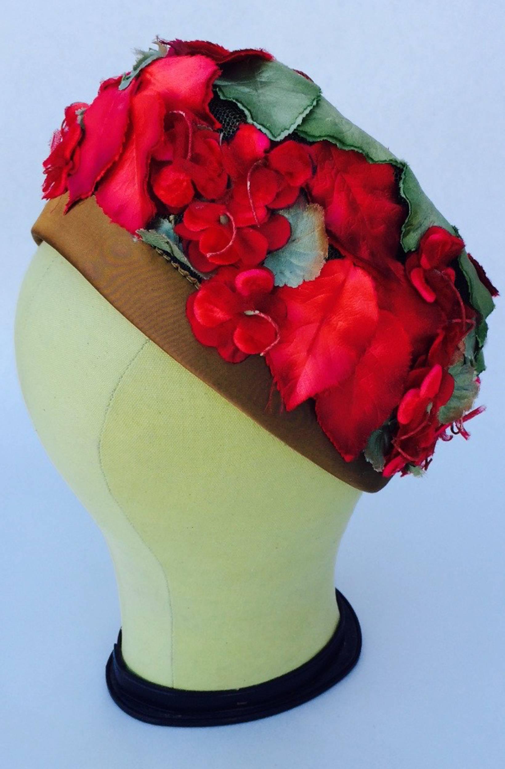 A fine vintage Schiaparelli floral trimmed turban. Authentic silk item features red and green flora on a olive silk trimmed turban. Item intact with no issues. Original shocking pink signature box intact. Excellent appears unworn.