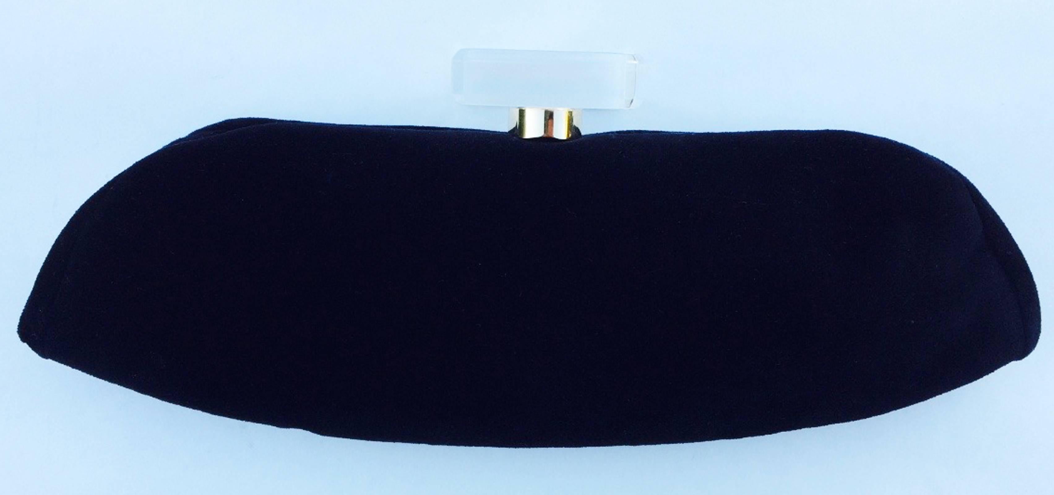 A fine and rare vintage Chanel hand clutch. Authentic black velvet item features a large gilt logo embedded Lucite bottle stopper decked clasp closure. Item fully leather lined with id card intact. Lucite stopper measures 2