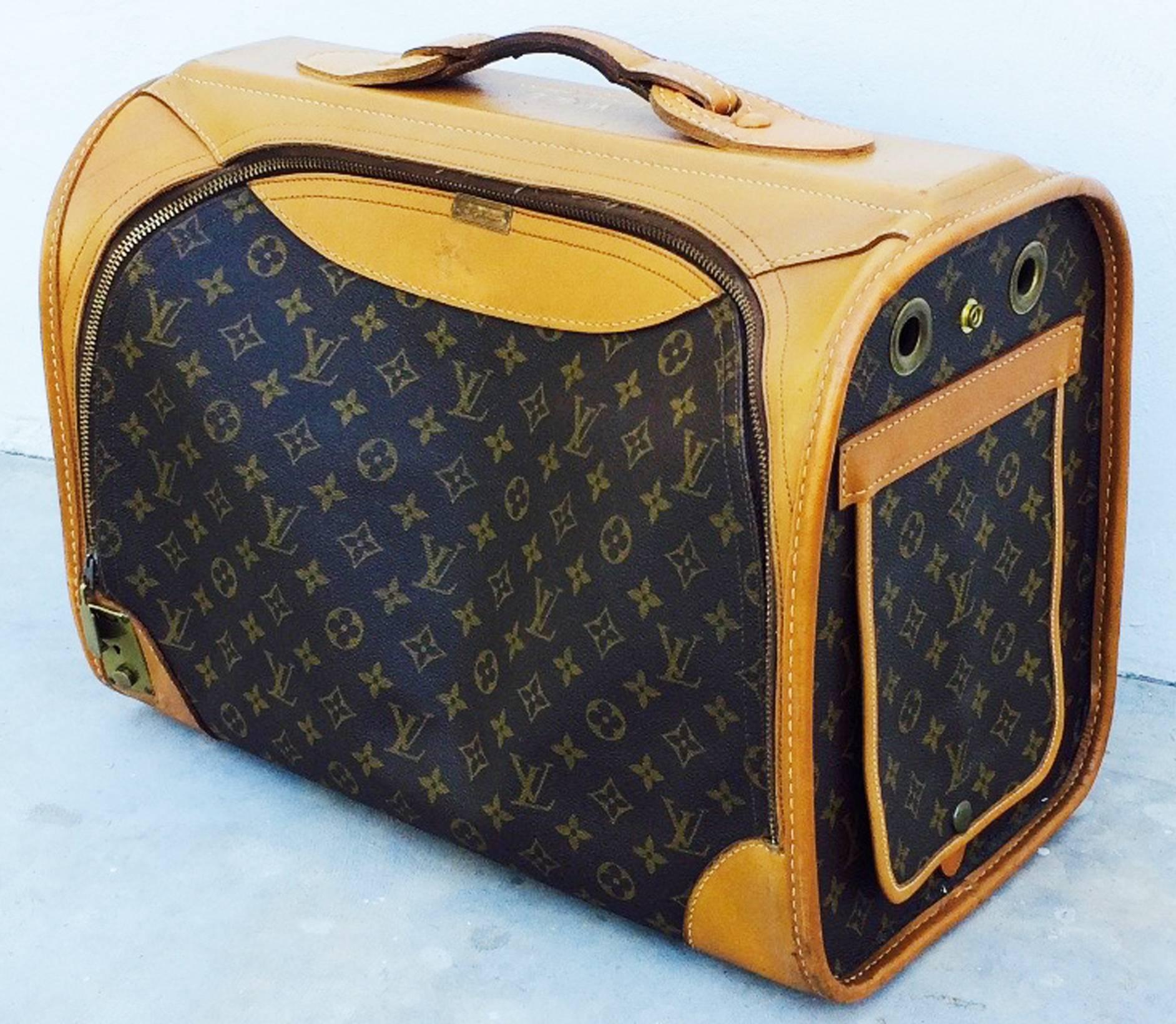 William de Lillo's Louis Vuitton sac chien dog carrier case. Authentic logo canvas item trimmed in leather with brass hardware and glides. Vinyl lined interior features a zipper closure, rolling mesh window and air vents. Item monogramed for Mr. de
