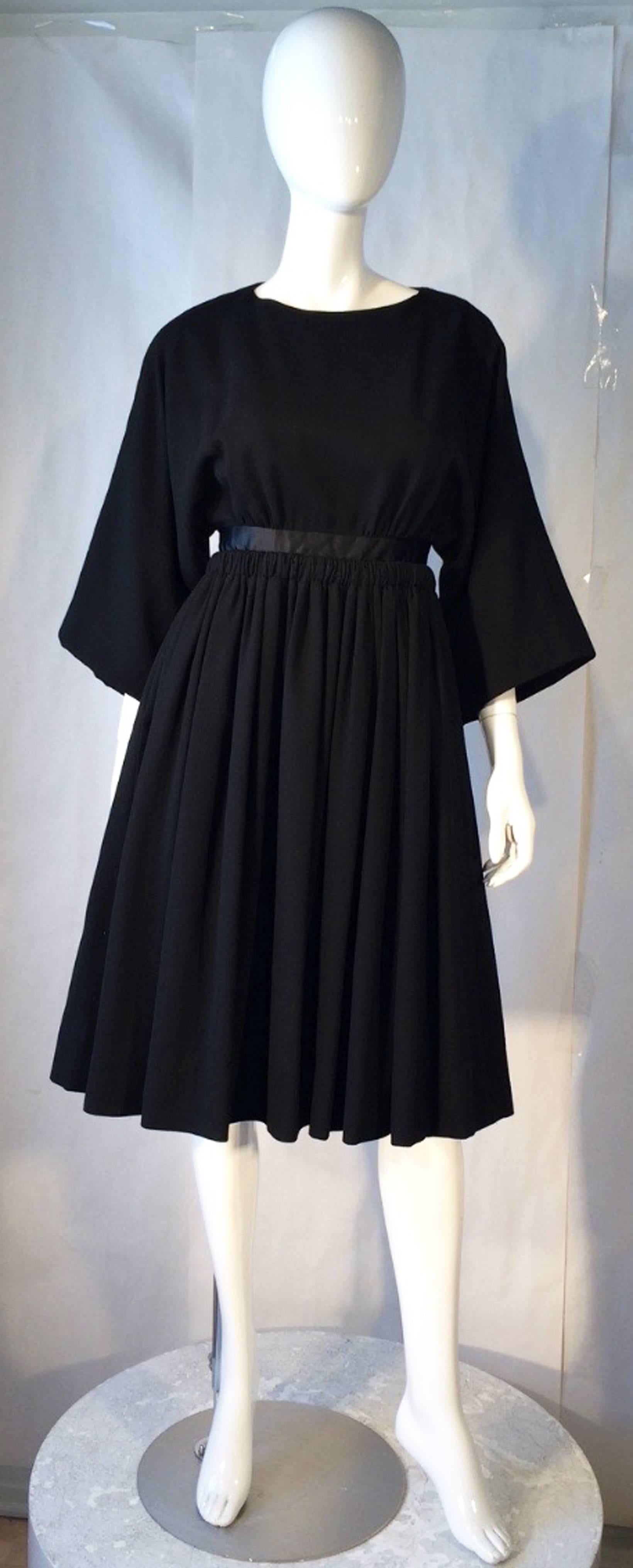 A fine and rare vintage James Galanos cocktail dress. Item sourced directly from original owner and purchased, 1953 (Blum's-Vogue, Chicago). Black wool crepe item features a full pleated skirt, nipped waist with a jet silk waistband and full