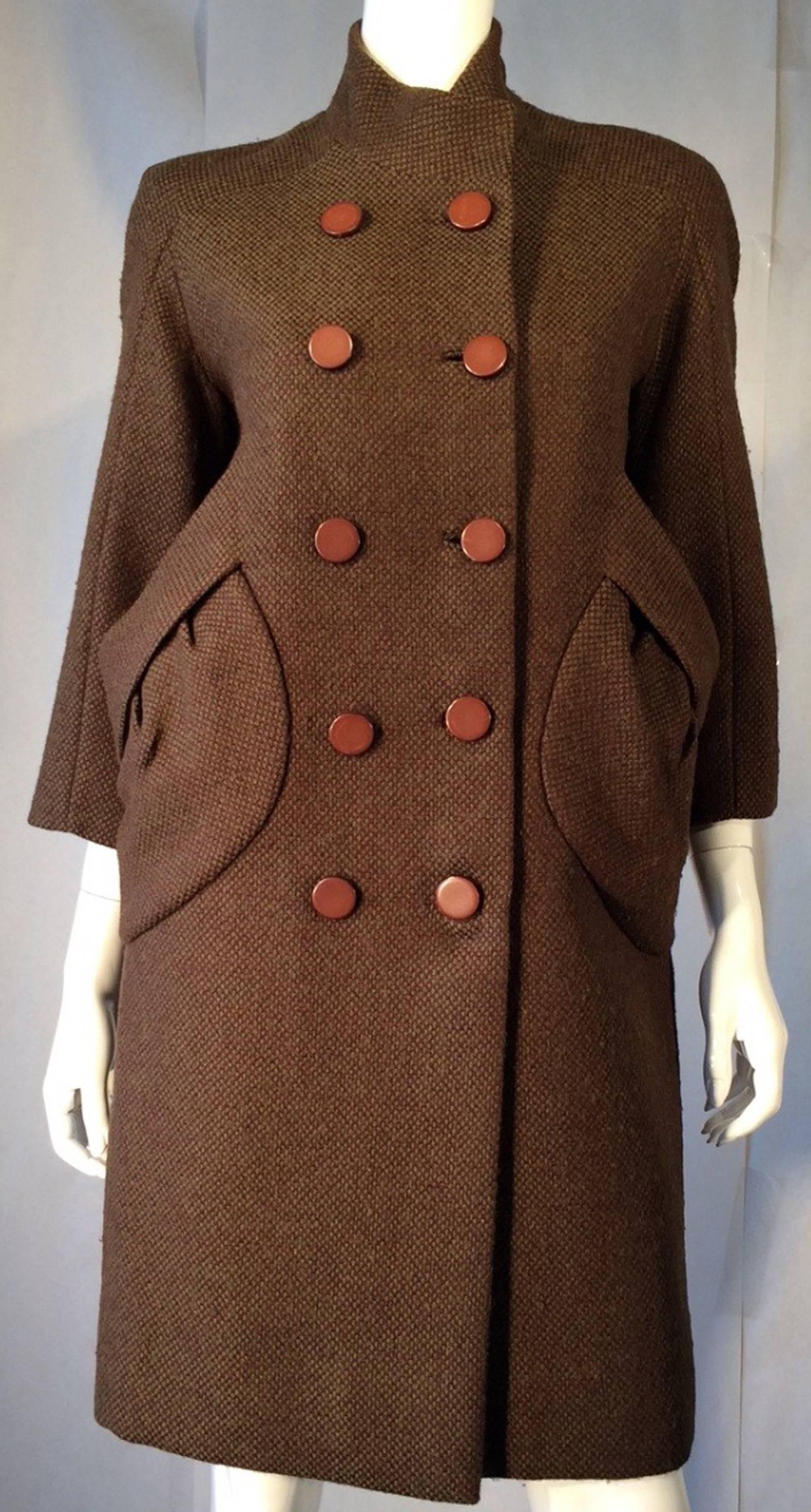 A fine vintage Jacques Heim sculpted coat. Fine olive woven wool item features a pair of unusual sculpted side pockets and double breasted button front. Item fully silk lined with precision seams. Pristine appears possibly unworn.