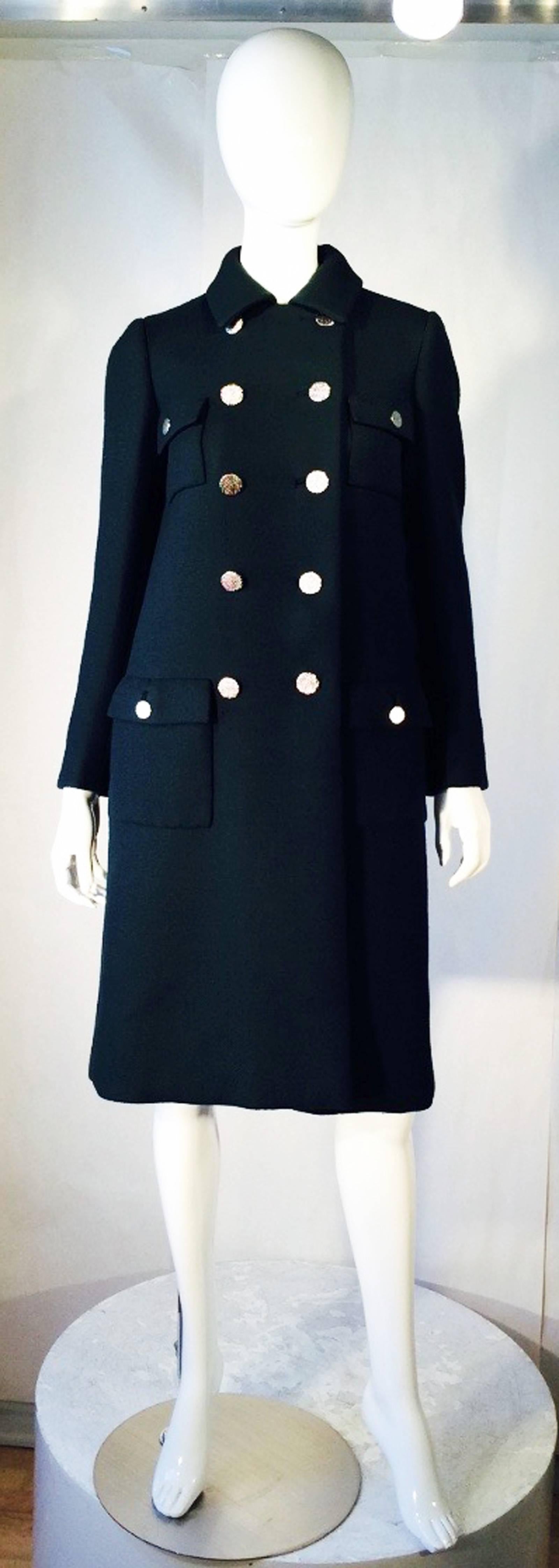 A fine and rare vintage Norman Norell military-style coat. Authentic dark green ribbed woven wool fabric item fully silk lined with a double breasted button front, attached half back belt and square patch pockets. Original sculpted silver-tone metal