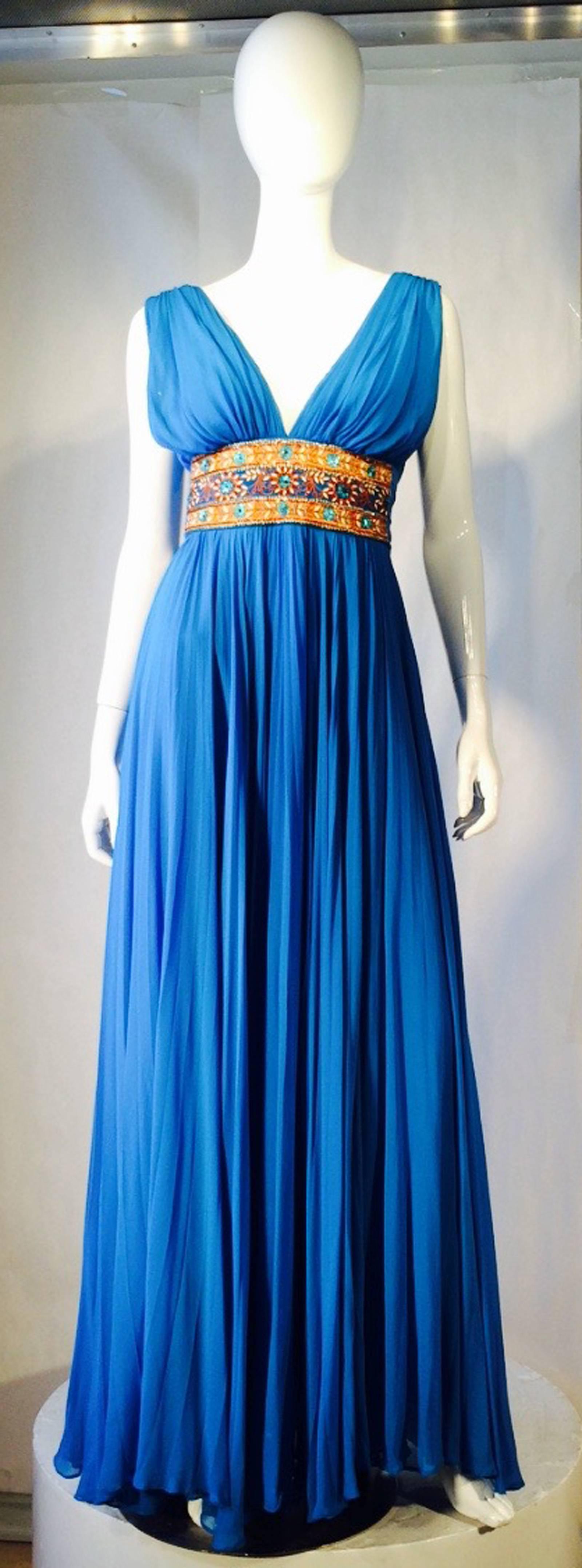 A gotgeous vintage Reem Acra Grecian column gown. Vibrant blue Azur silk chiffon item features a wide embroidered and beaded waistband, pleated bodice and skirt. Item fully silk lined and zips up back. Exquisite hand-finished item appears unworn.