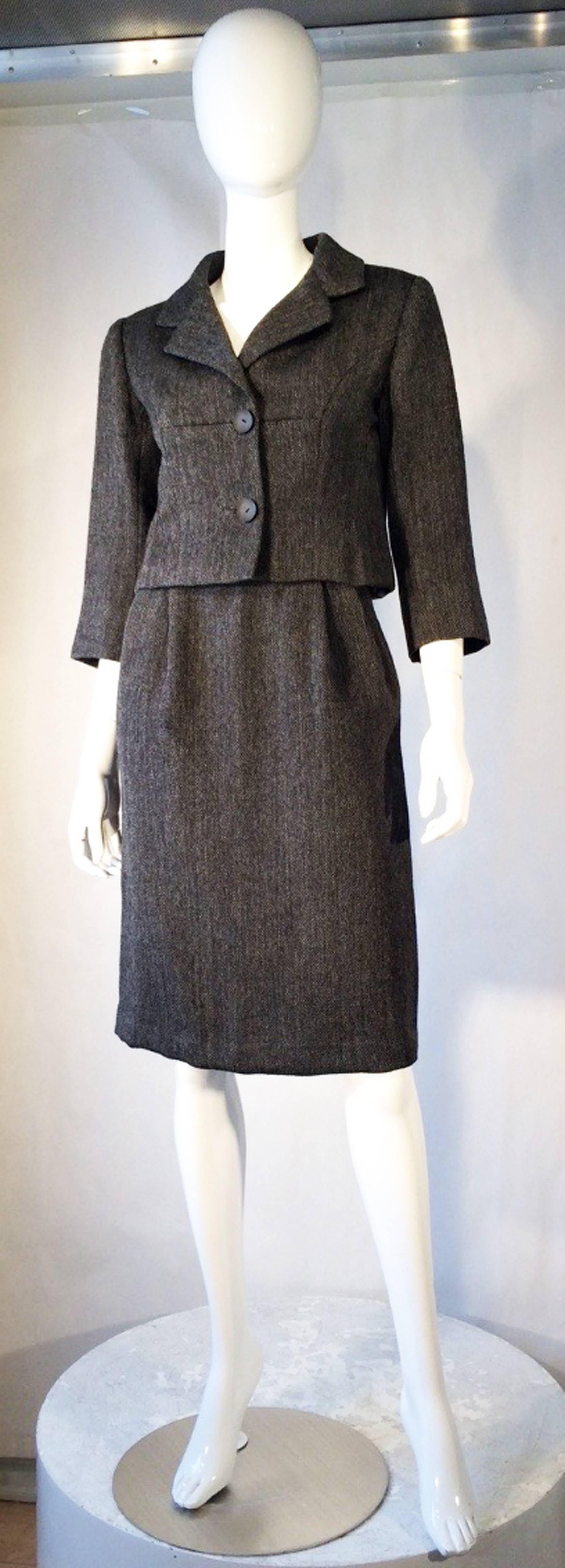 A fine and rare vintage Balenciaga haute couture skirt suit. Authentic numbered item circa 1957. Exquisite charcoal 2pc. wool tweed fabric items feature precision seams with original buttons, zippers, hooks and silk lining. Excellent item with no