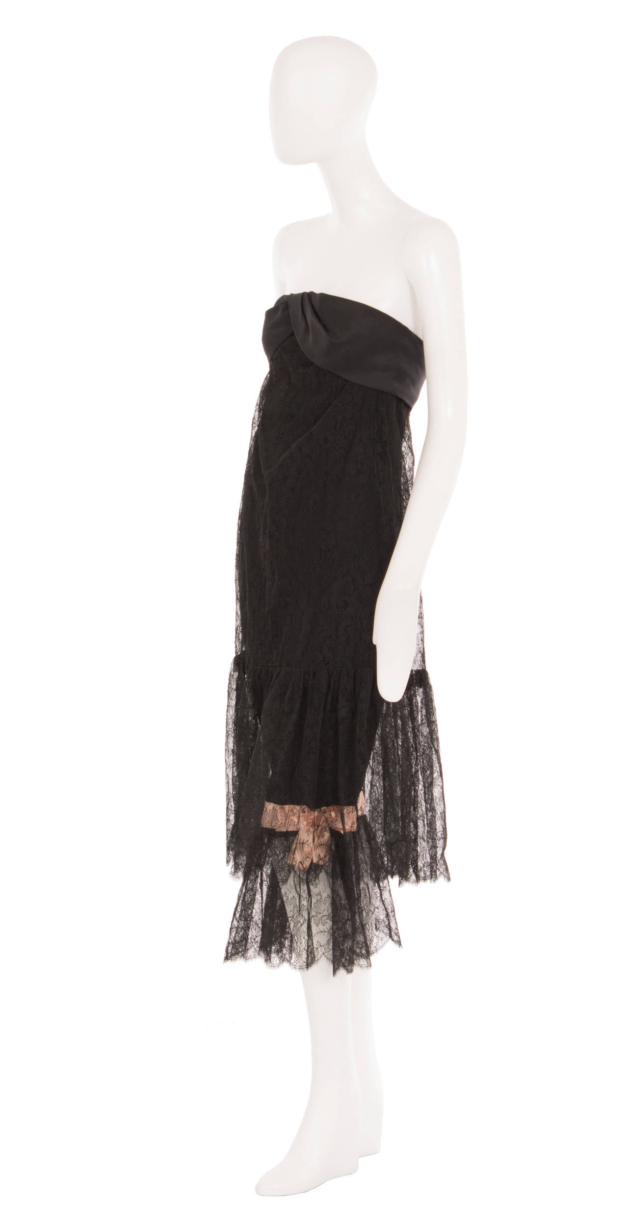 A rare piece of haute couture by Balenciaga for his Eisa label, this cocktail dress features a pair of integral pantalettes. Constructed of black Chantilly lace, the strapless dress features a bandeau of black silk taffeta across the bust, and a