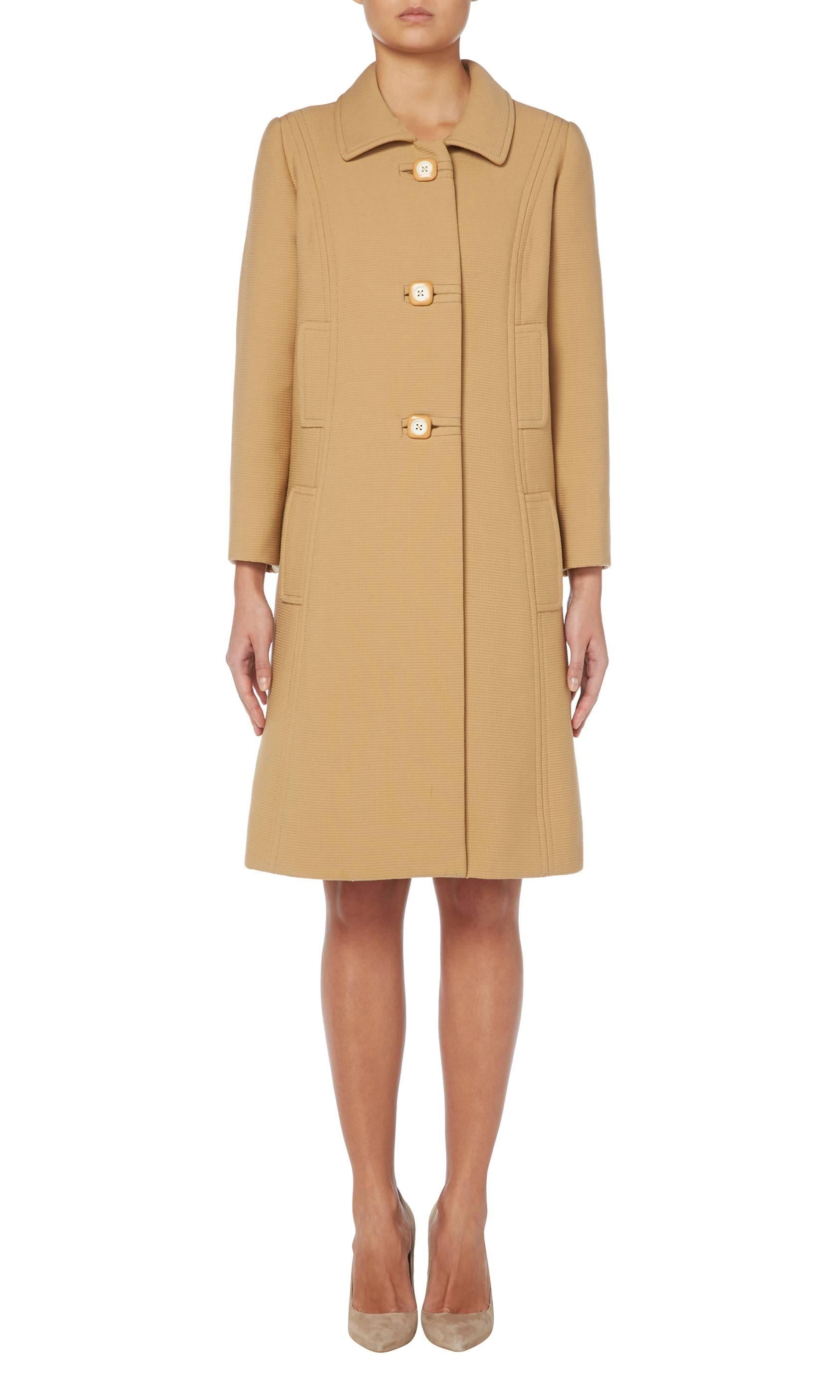 A fantastic wardrobe staple, this Balmain haute couture coat is perfect for all year round. Constructed in camel coloured ribbed wool, the coat has a classic 60s silhouette with a single lapel collar and bracelet length sleeves. The square plastic