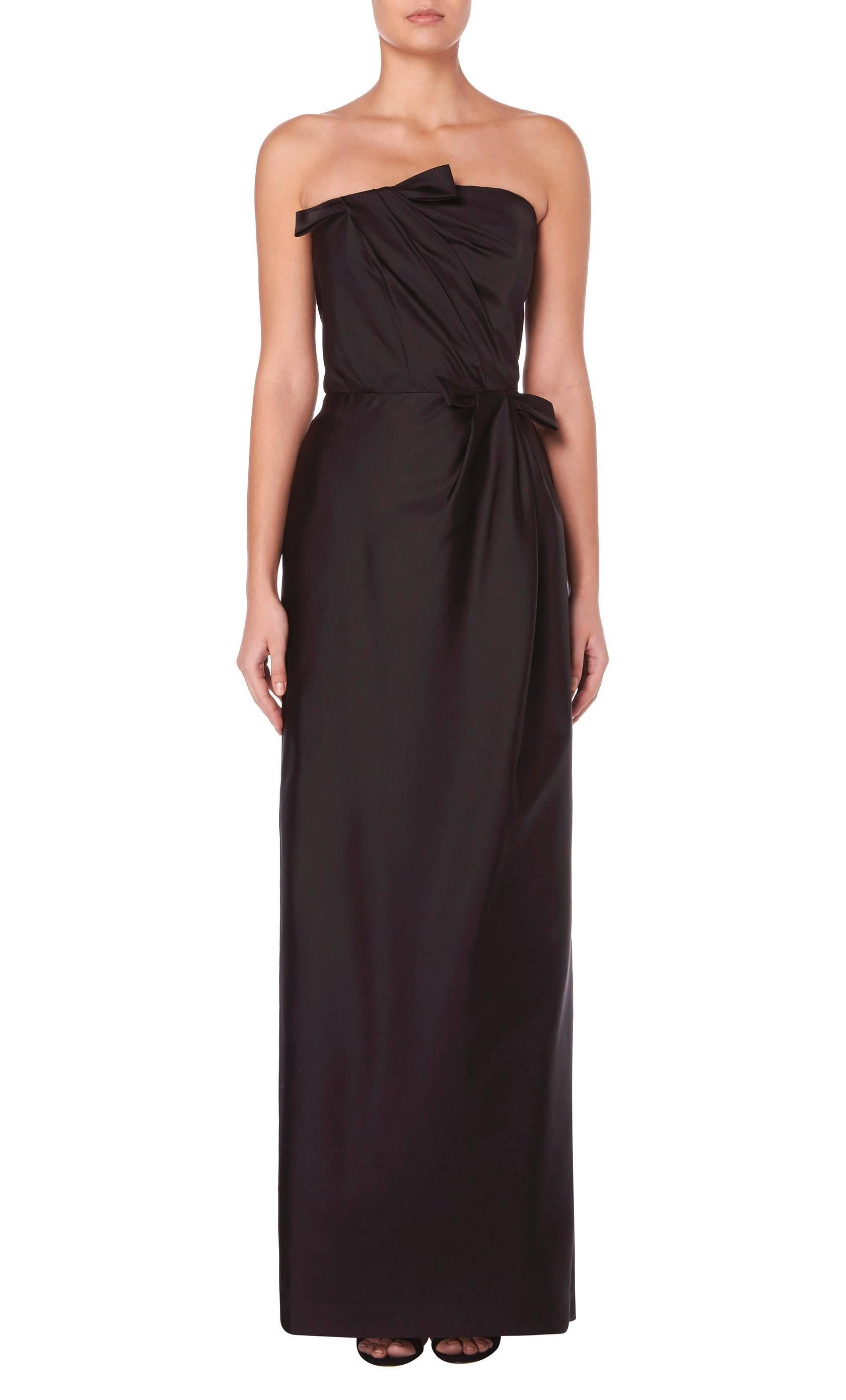 Effortlessly elegant, this Bill Blass strapless gown is ideal for red carpet events. Constructed in black silk taffeta, the gown features artful asymmetric gathering on the bodice, and skirt finished with a bow details at the bust and waist. The