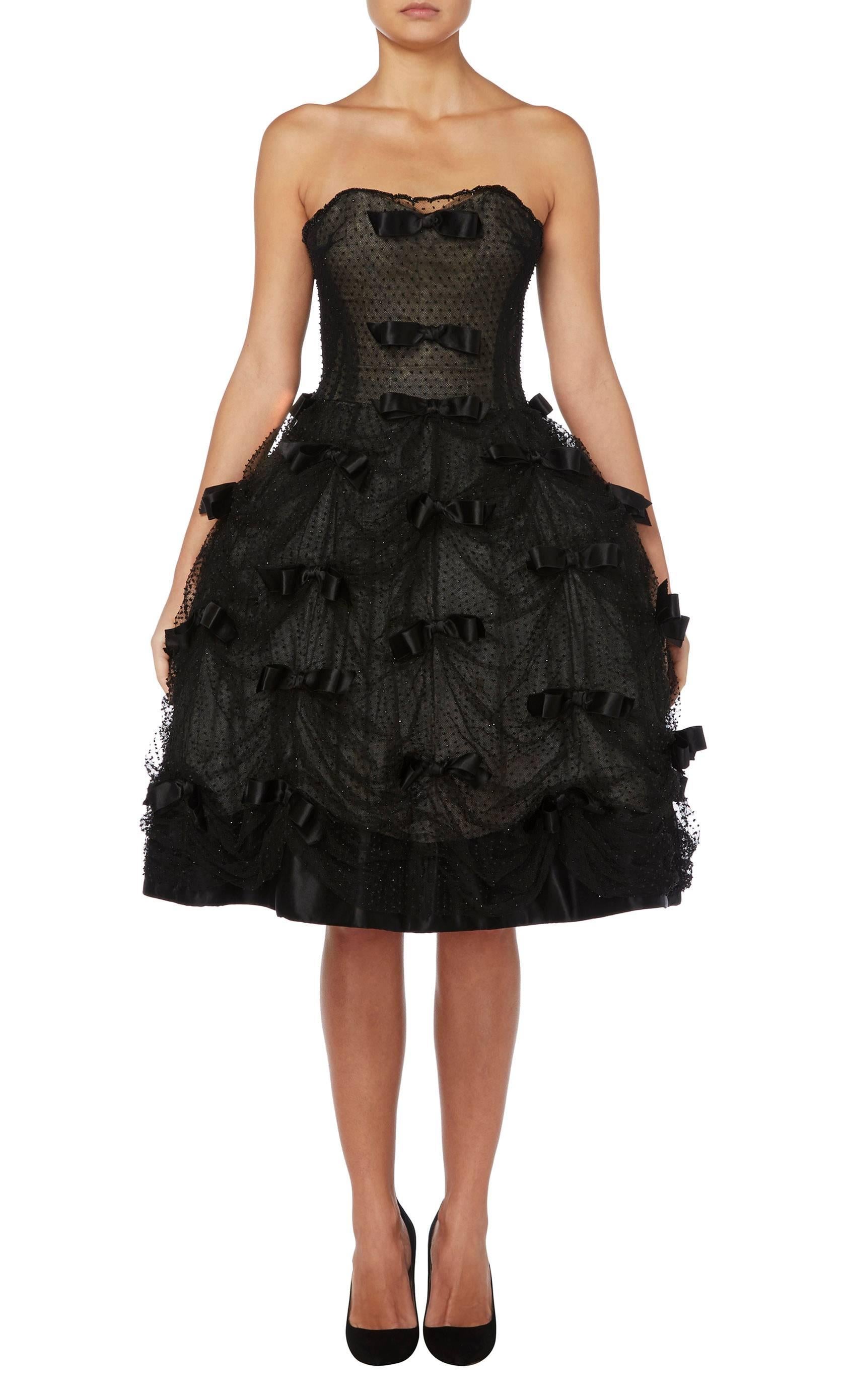 Constructed in black silk and ivory tulle
Featuring black glass bugle bead and silk satin bow embellishment
Hook and eye fastenings to the side
Excellent condition with the original label, boning and underskirts
Professionally dry cleaned and