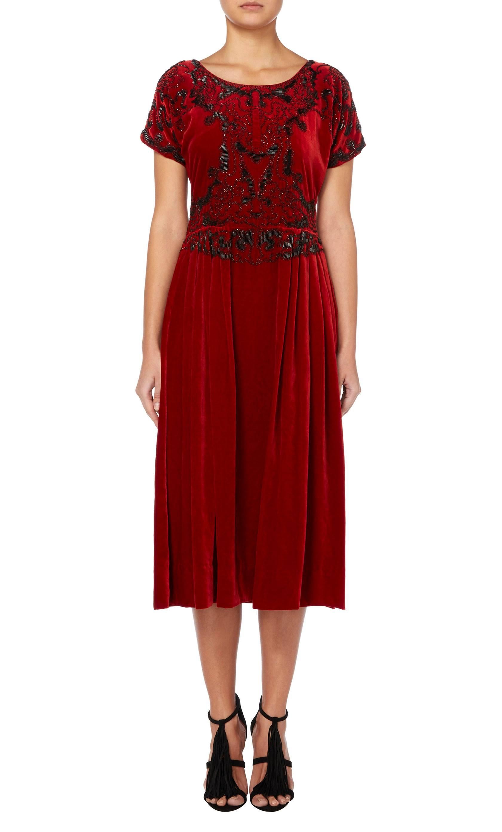 Designed by the legendary Paul Poiret in c1925, this haute couture cocktail dress is an exceptional example of the designers work. Constructed of the finest ruby red silk velvet, the dress is intricately embroidered with black glass bugle beads on