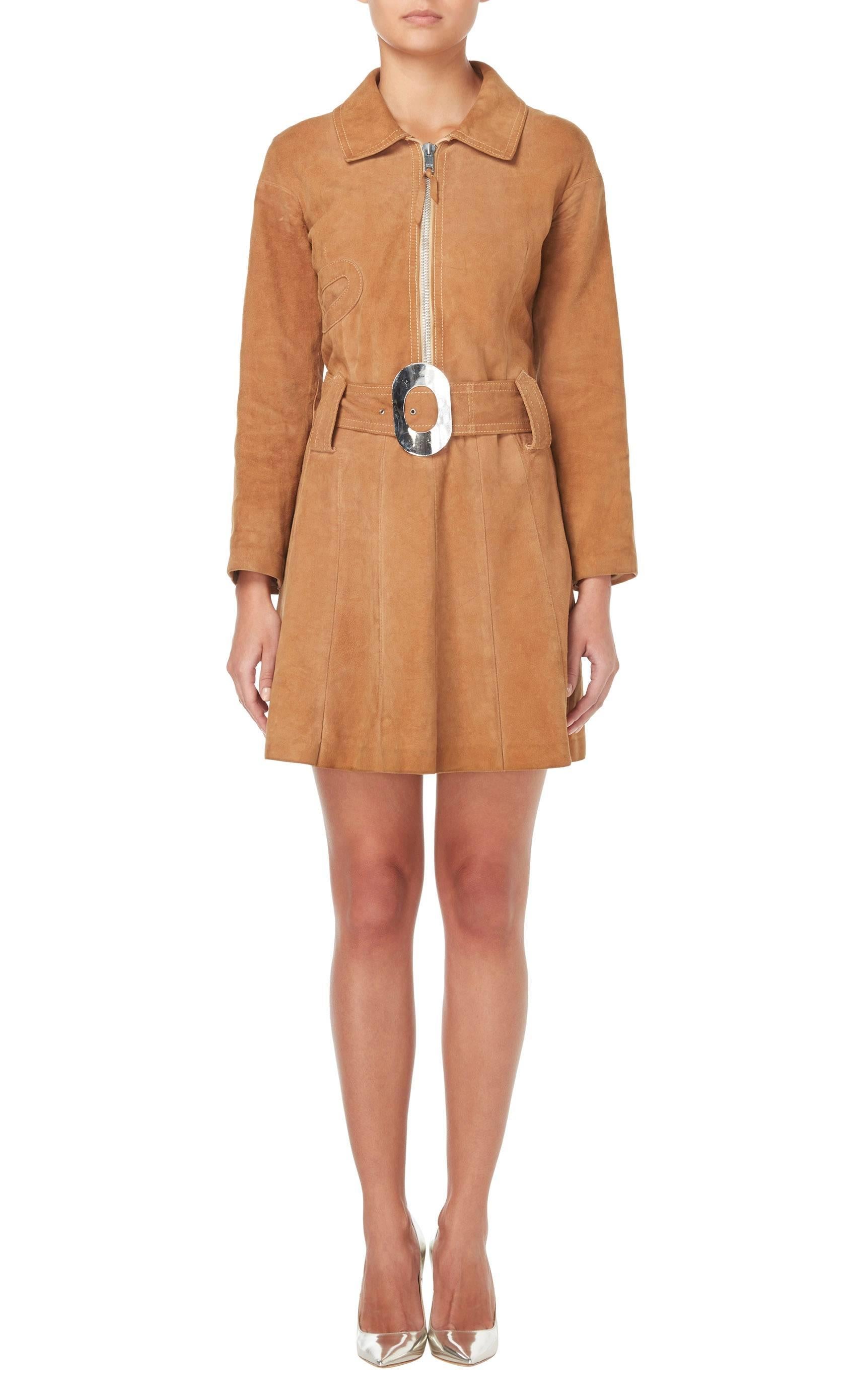 This Pierre Cardin brown suede dress is a fun piece that will fit perfectly within a contemporary wardrobe. Constructed in soft tan suede, the dress features a collar and long sleeves, which balance out the shorter length of the skirt. A chunky zip