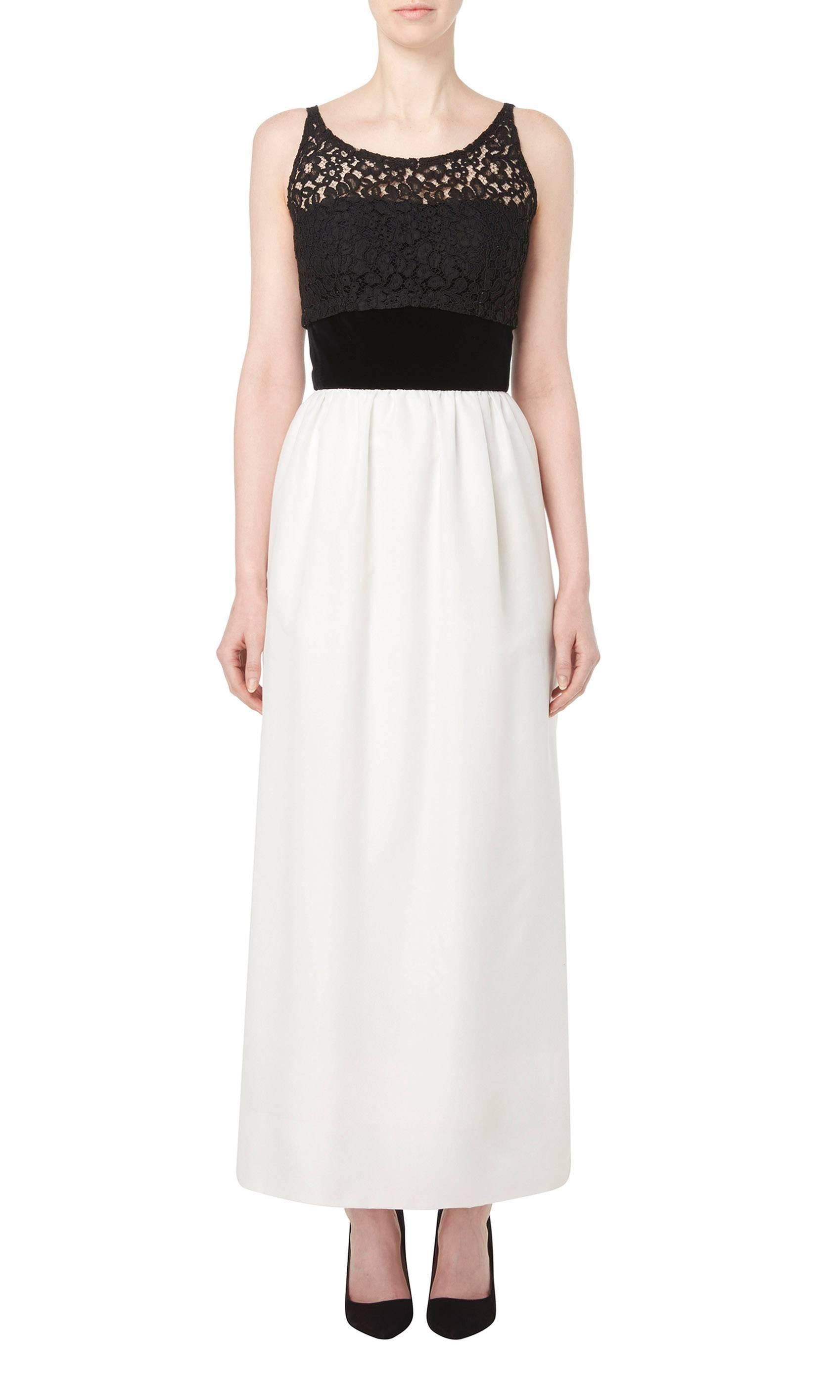 This stunning monochrome evening dress by Jacques Heim is made up of a black lace top, black velvet waistband and ivory silk skirt. The dress features a flattering scooped neckline, plunging lower at the back, with a split between the lace and