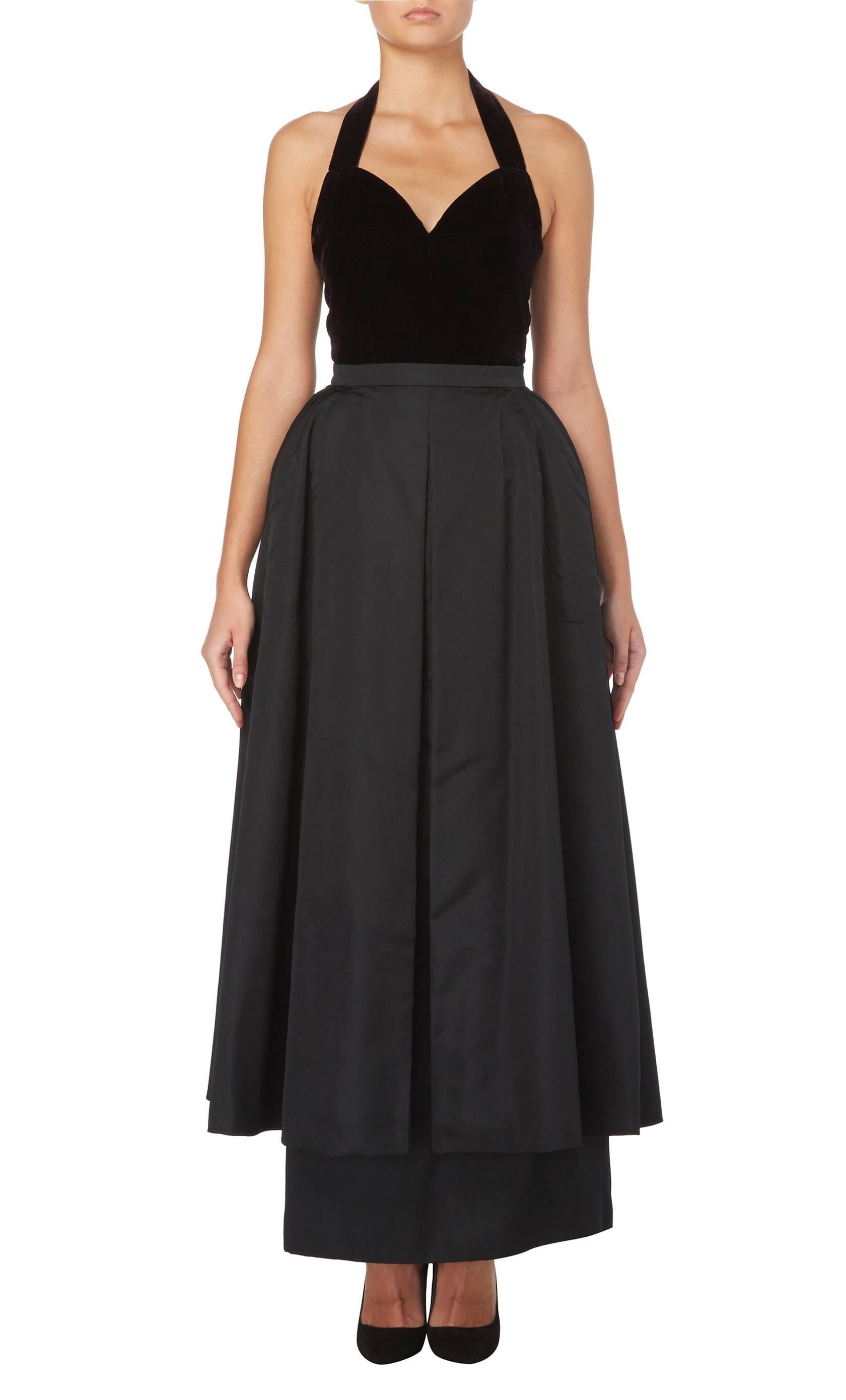 This utterly chic two-piece evening ensemble consisting of a velvet halter neck top and satin skirt is perfect for red carpet events. The top features a sweetheart neckline and fastens at the back of the neck with hook and eyes. The skirt has two