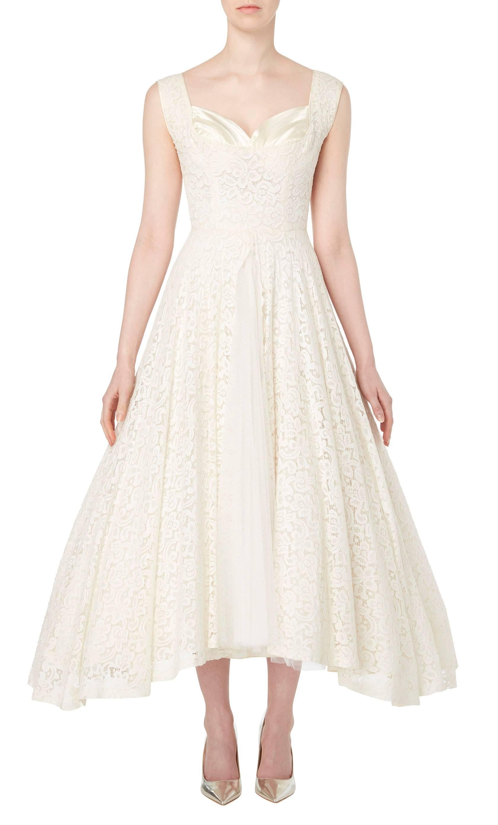 A stunning option for a wedding or summer party, this Jean Patou haute couture dress is the epitome of chic! Constructed in ivory lace, the dress features a sweetheart neckline with a pleated satin bust. The lace of the skirt is split up the front