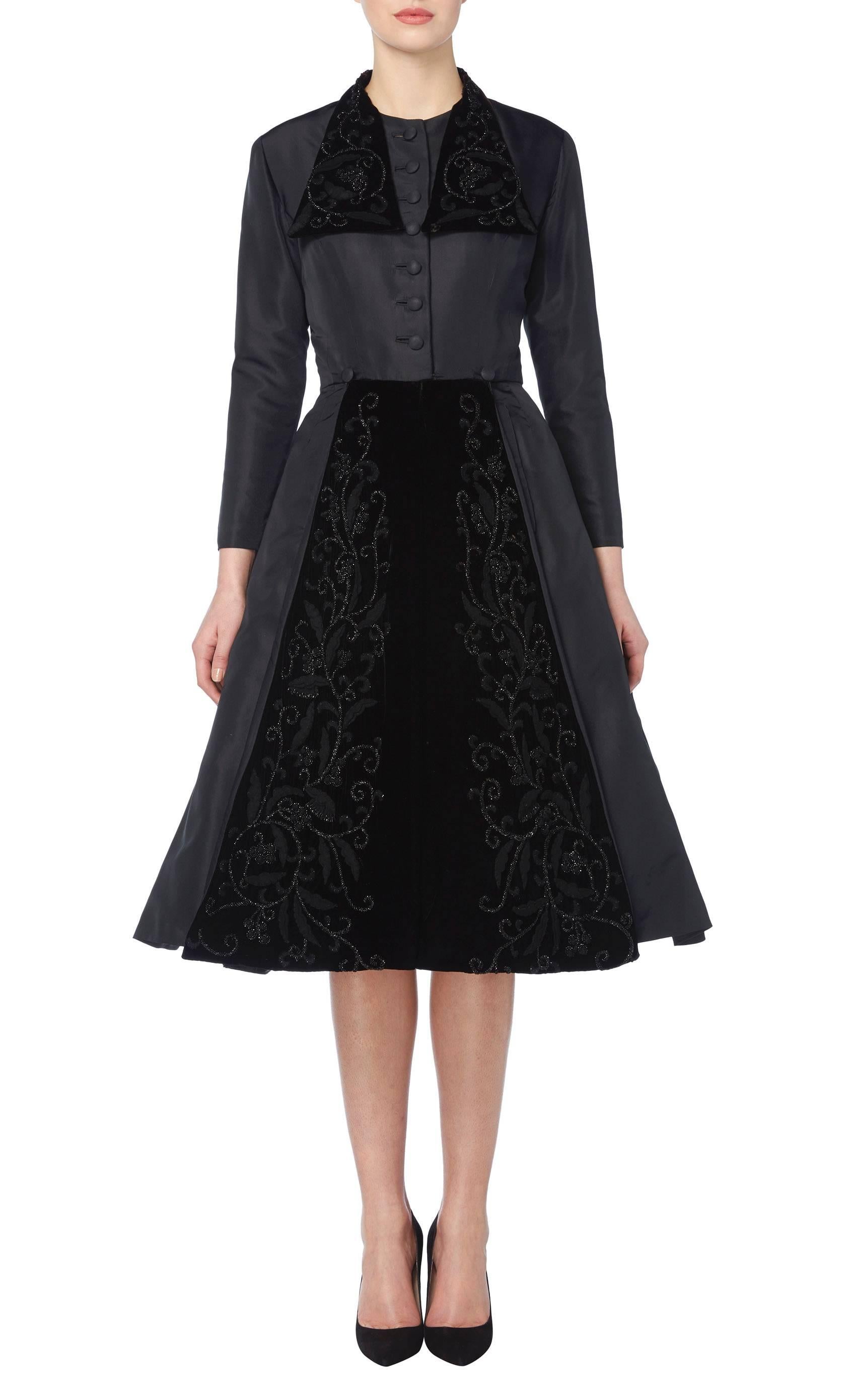 An incredible example of Dior's 'New Look', this dress coat is cut in the famous Dior silhouette, with a nipped in waist and wide skirt. The dress coat is constructed from black silk taffeta with panels of black velvet embroidery on the front of the