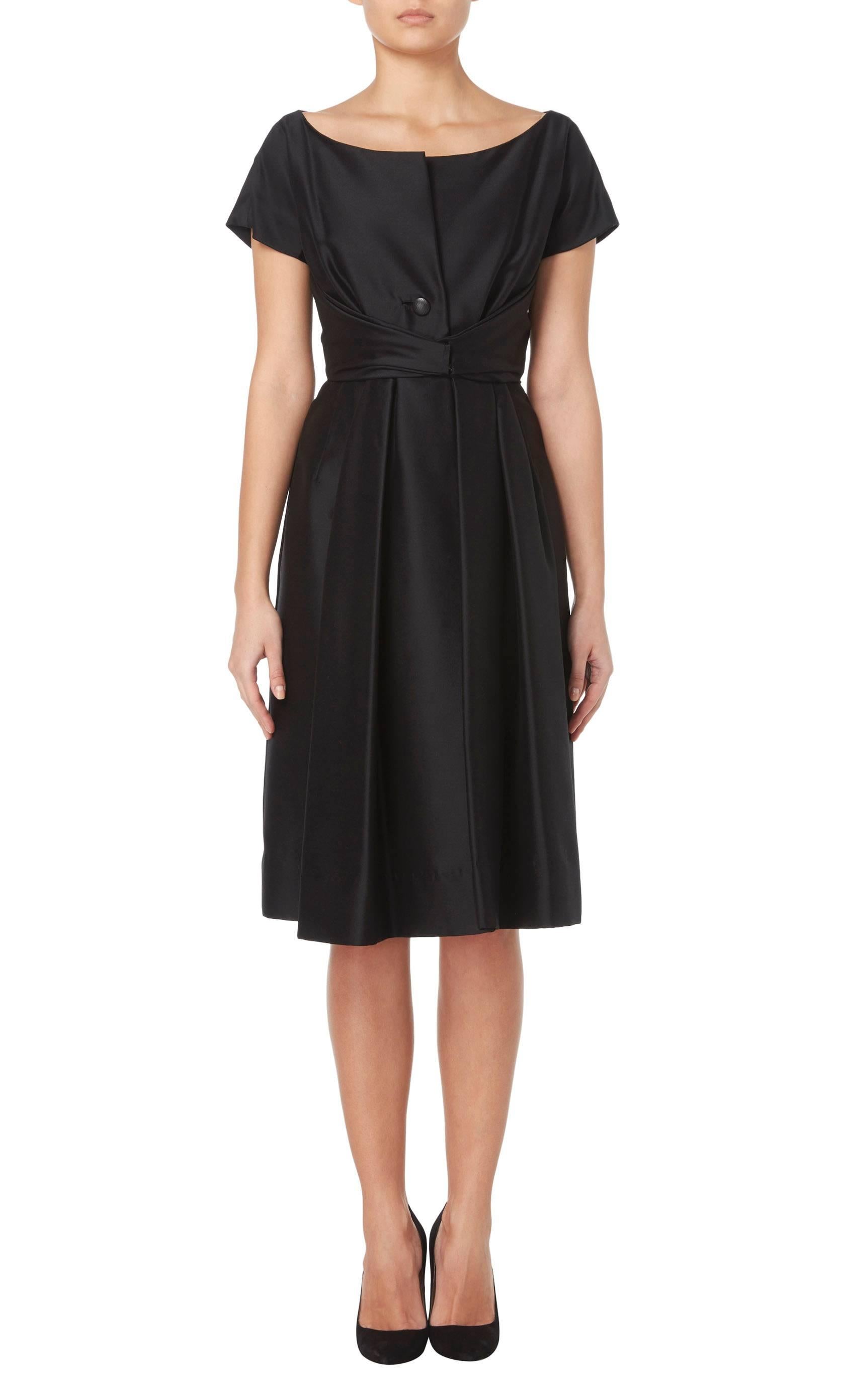 An ultimate vintage moment, few dresses are as iconic as a 1950s Dior LBD. With chic capped sleeves, a button front opening and hidden pockets on the hip, the dress has a classic Dior finishing touch with a front sash running from the waistband to