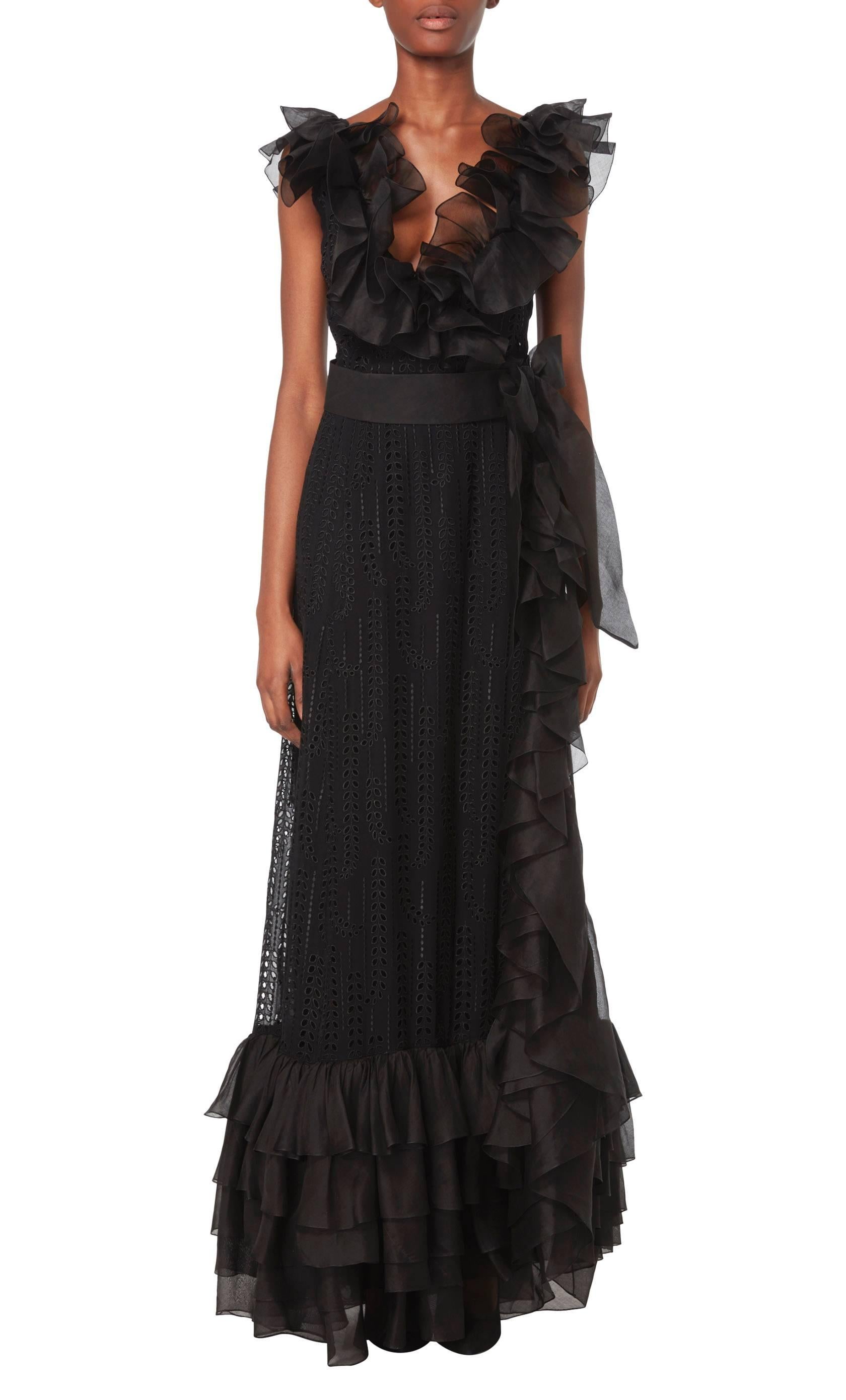 This dramatic Chanel haute couture dress is constructed in beautiful black silk georgette broderie anglaise, with a lining in the skirt and bust for opacity. The wrap front creates a flattering low-cut neckline, while a black organza belt with a bow