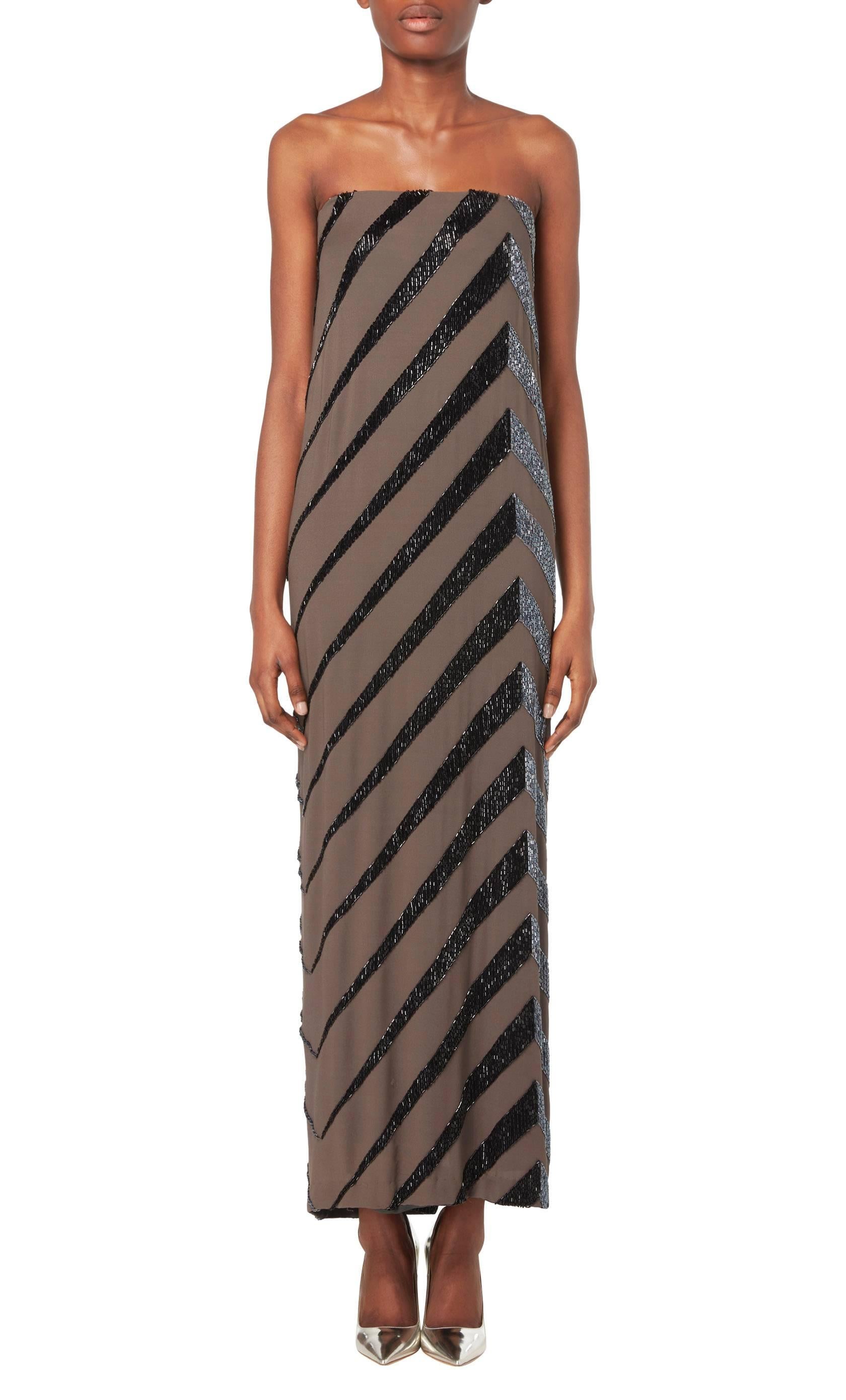 A striking dress by the legendary Bob Mackie, this strapless column dress in chocolate brown silk jersey is embellished with gunmetal grey bugle beads. Slinky, chic and perfect for injecting glamour into a wardrobe.

Constructed in brown silk