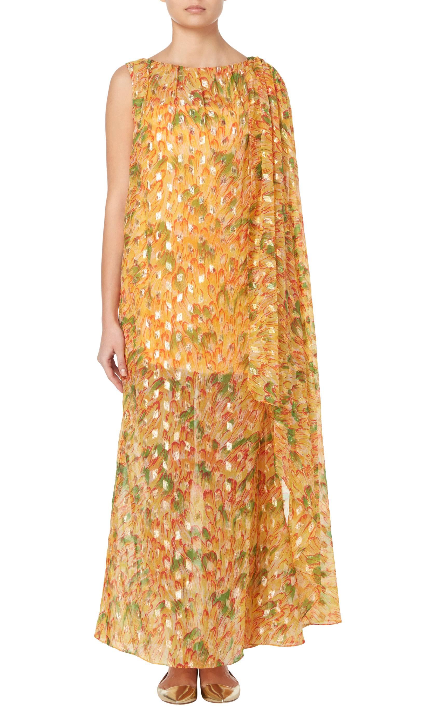 This metallic Malcolm Starr maxi dress is ideal for pool parties or sunset cocktails. Constructed in sheer orange, green and red printed synthetic chiffon, and shot though with gold metallic thread which sparkles in the light, the dress has a half