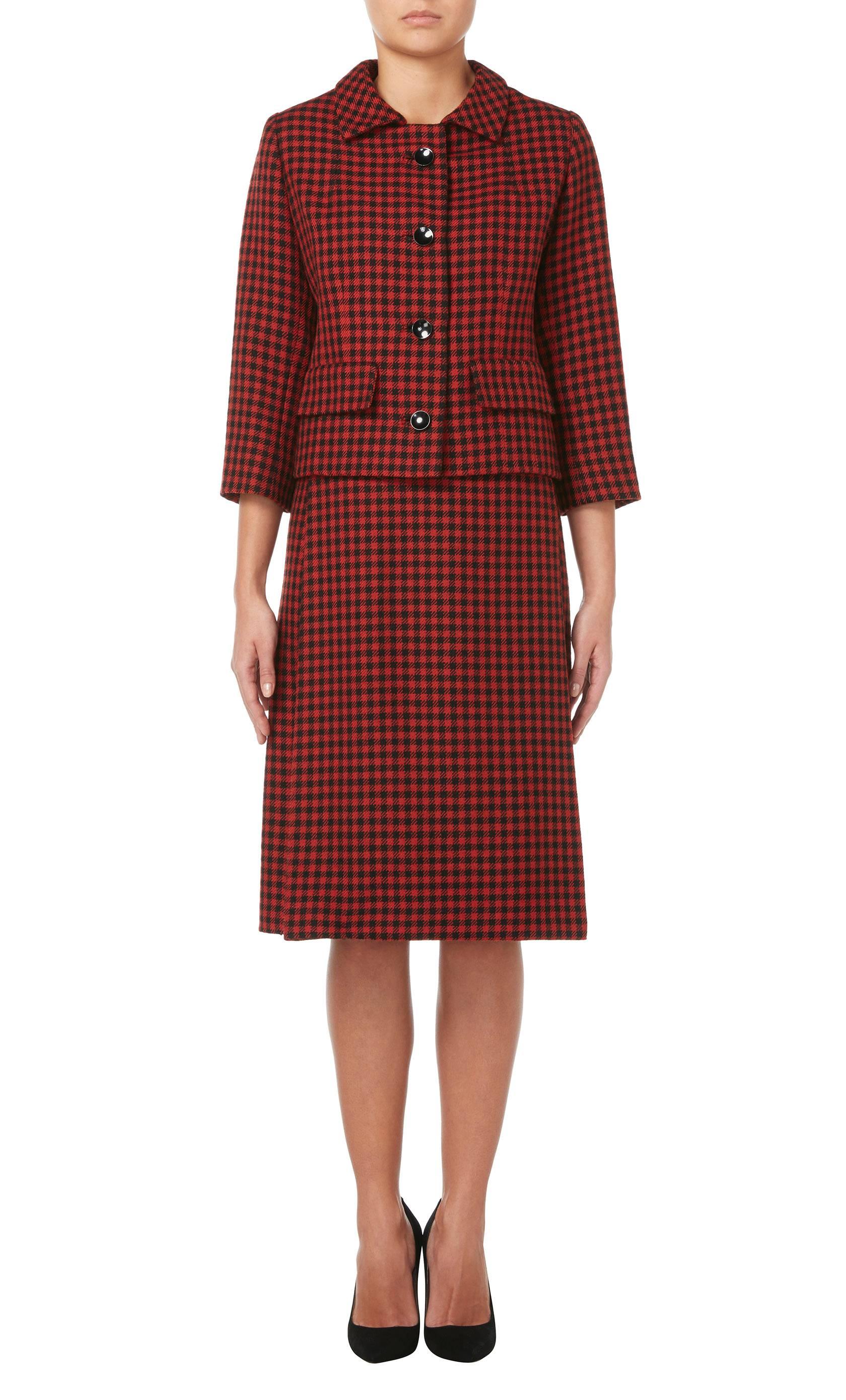 A fantastic example of Balenciaga's tailoring for his early Eisa label, this skirt suit is constructed in red and black houndstooth wool and lined in black silk. The jacket features a single lapel collar, black buttons fastening to the front and