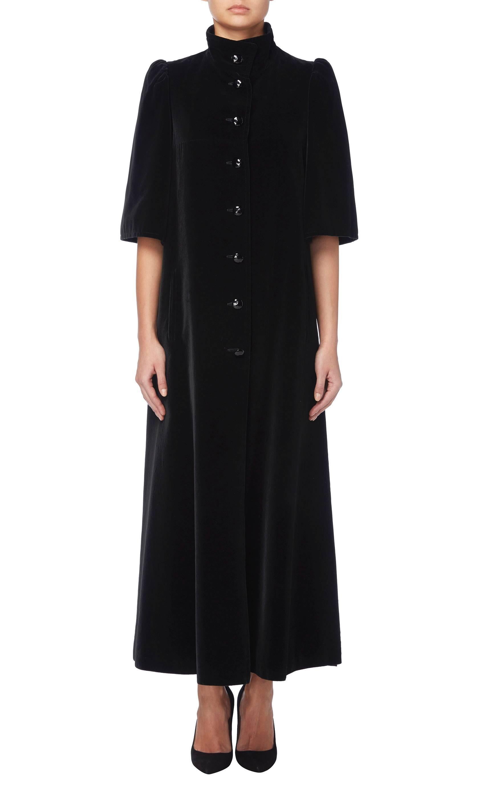 This Louis Féraud black velvet evening coat will add drama to an evening look. The standing collar elongates the silhouette, while the shorter sleeves are perfect for pairing with elbow length gloves. The black faceted buttons add subtle shine and