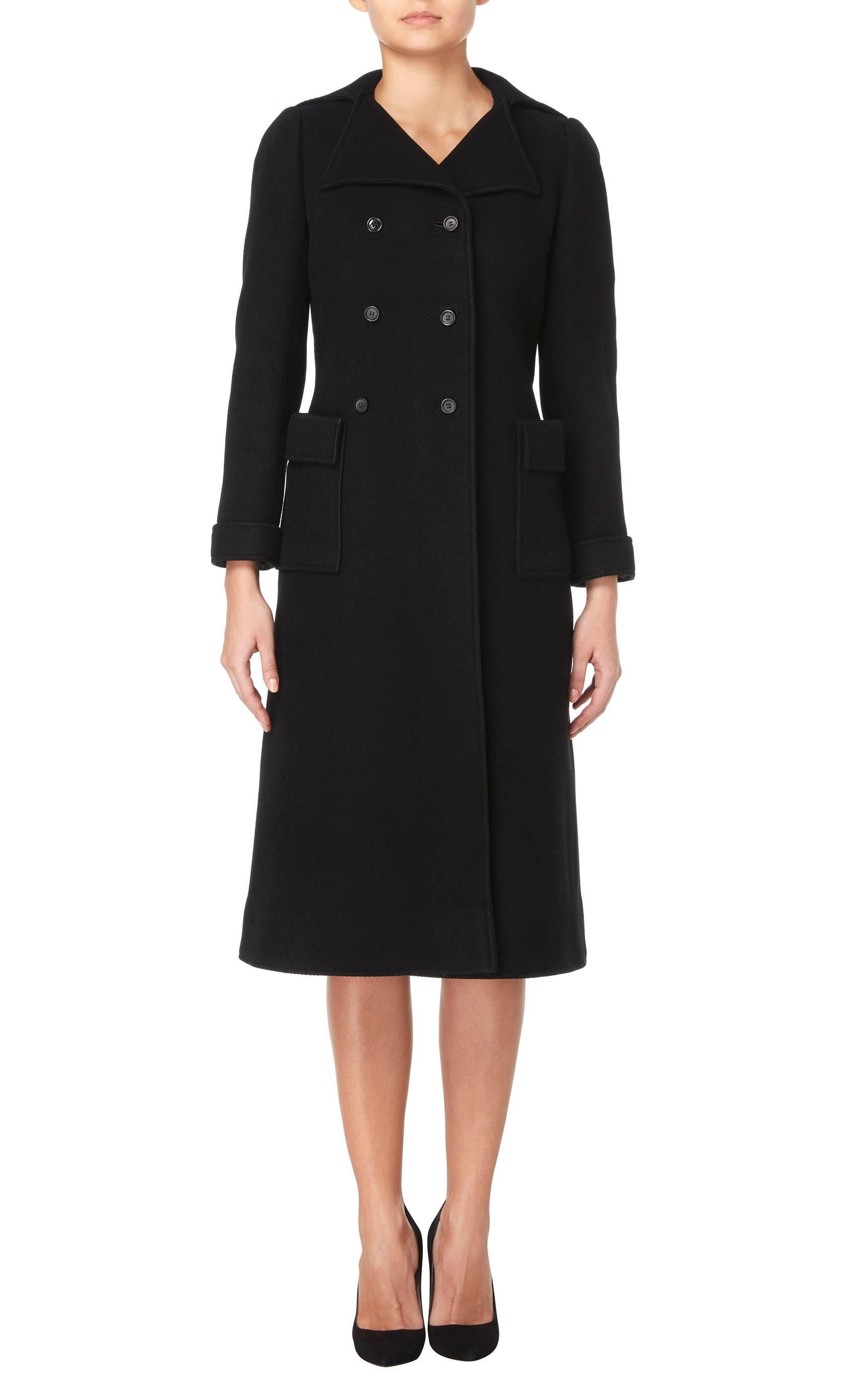 This classic Courrèges coat would make a fantastic addition to any modern wardrobe. Double-breasted and constructed in black wool, this piece will instantly become a wardrobe staple. Featuring a double lapel collar, half belt to the rear and