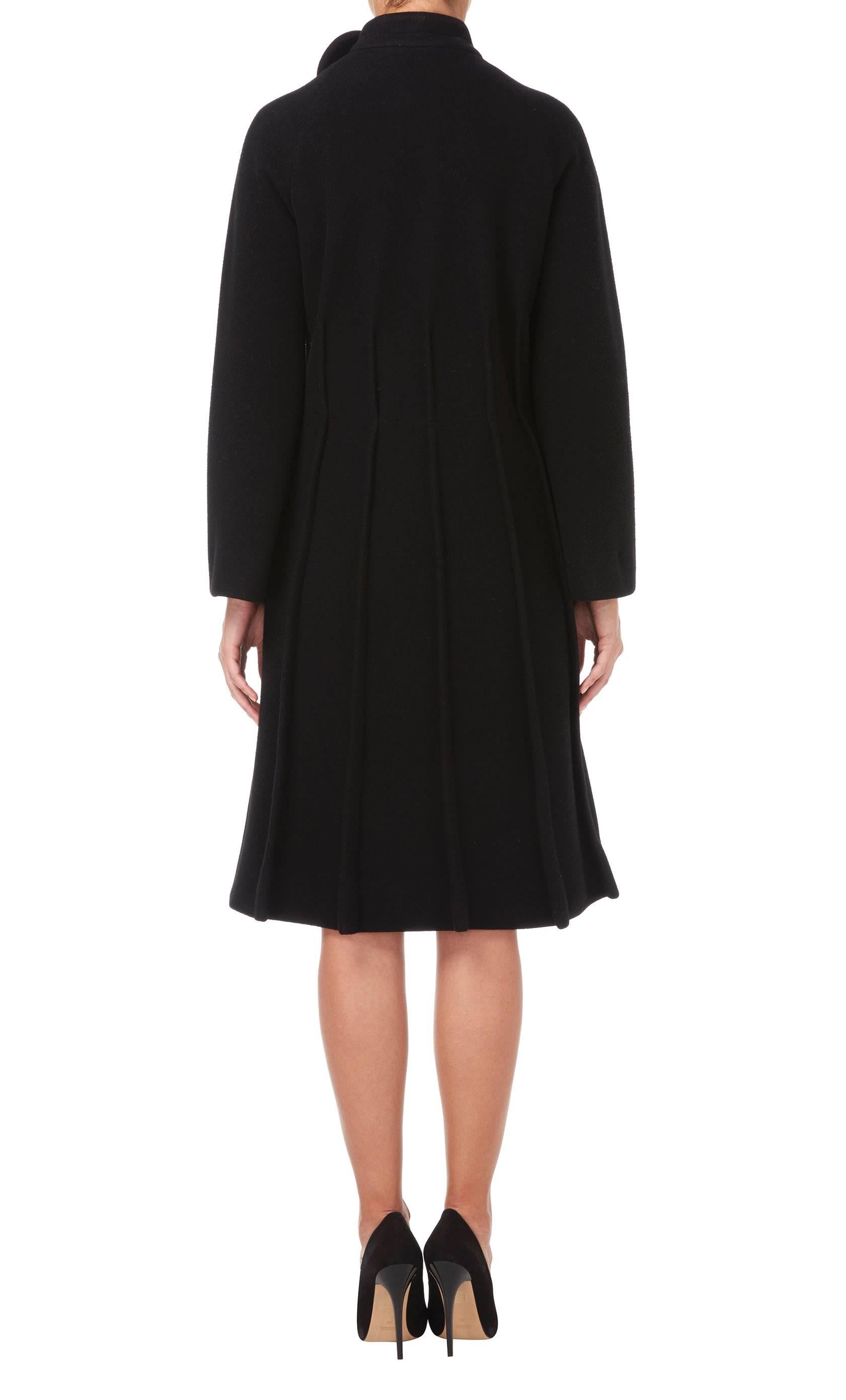An amazing example of Pierre Cardin's modernist aesthetic, this black wool coat has a fantastic silhouette. Inverted seam detailing from the waist down creates a pleated effect, while a circle motif on the standing collar is indicative of Cardin's
