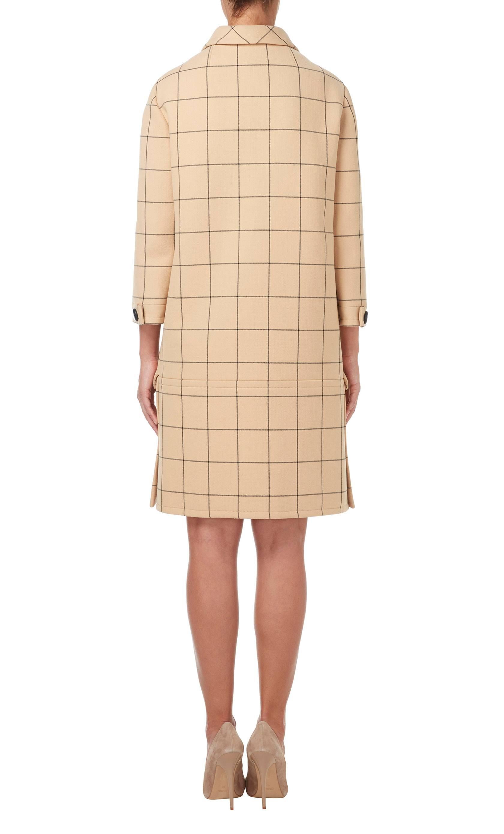 This beautifully cut coat, in light brown wool with a black windowpane check, is a fantastic piece for Autumn and Winter. Worn with knee high boots and a hat, this coat will keep you warm whilst staying chic. The boxy silhouette is contrasted with