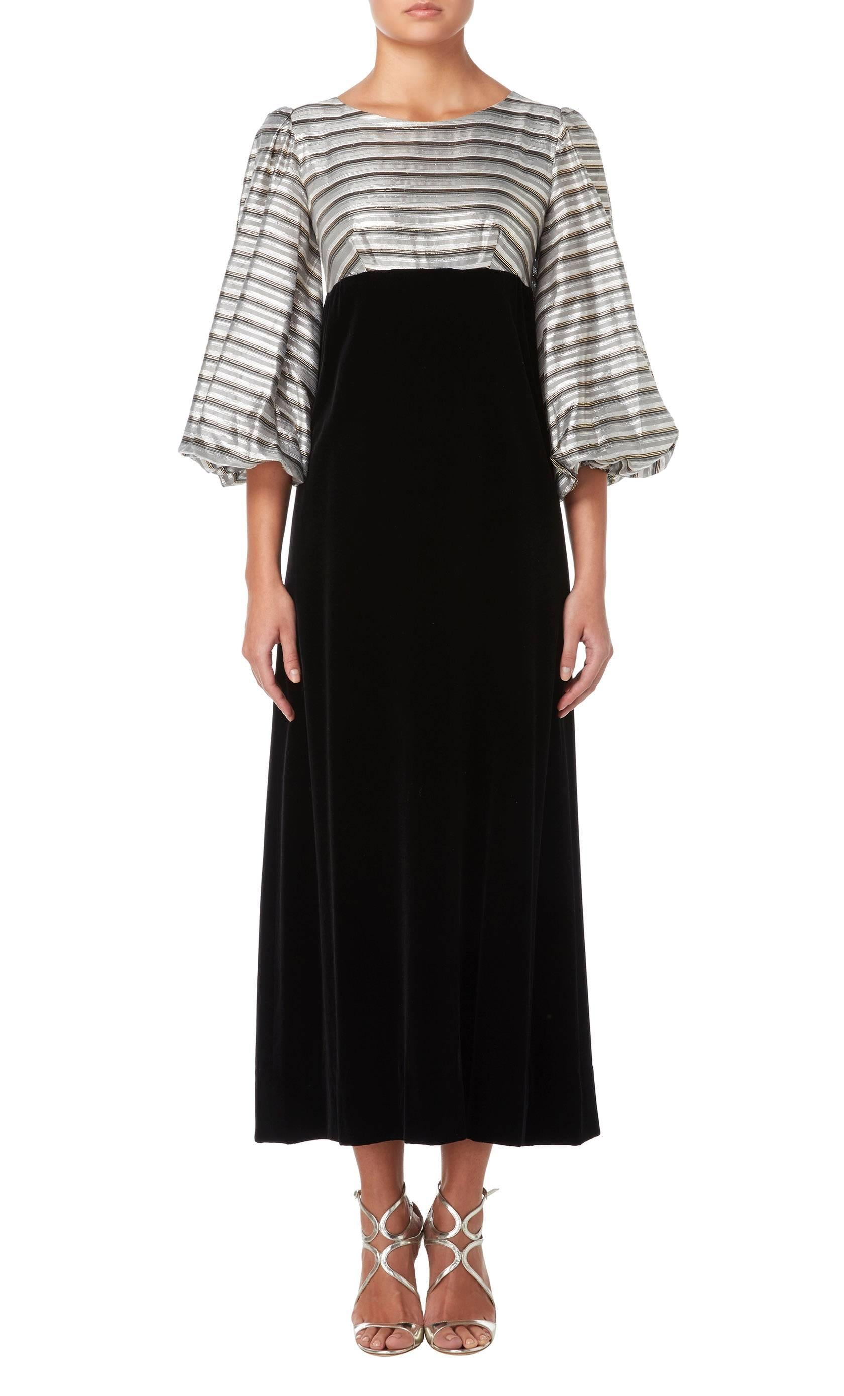 This Jean Varon maxi dress would make a fun option for a party or event. The body and wide balloon sleeves are constructed in a metallic fabric featuring horizontal strips in grey, silver, gold and black, while the black velvet skirt falls from