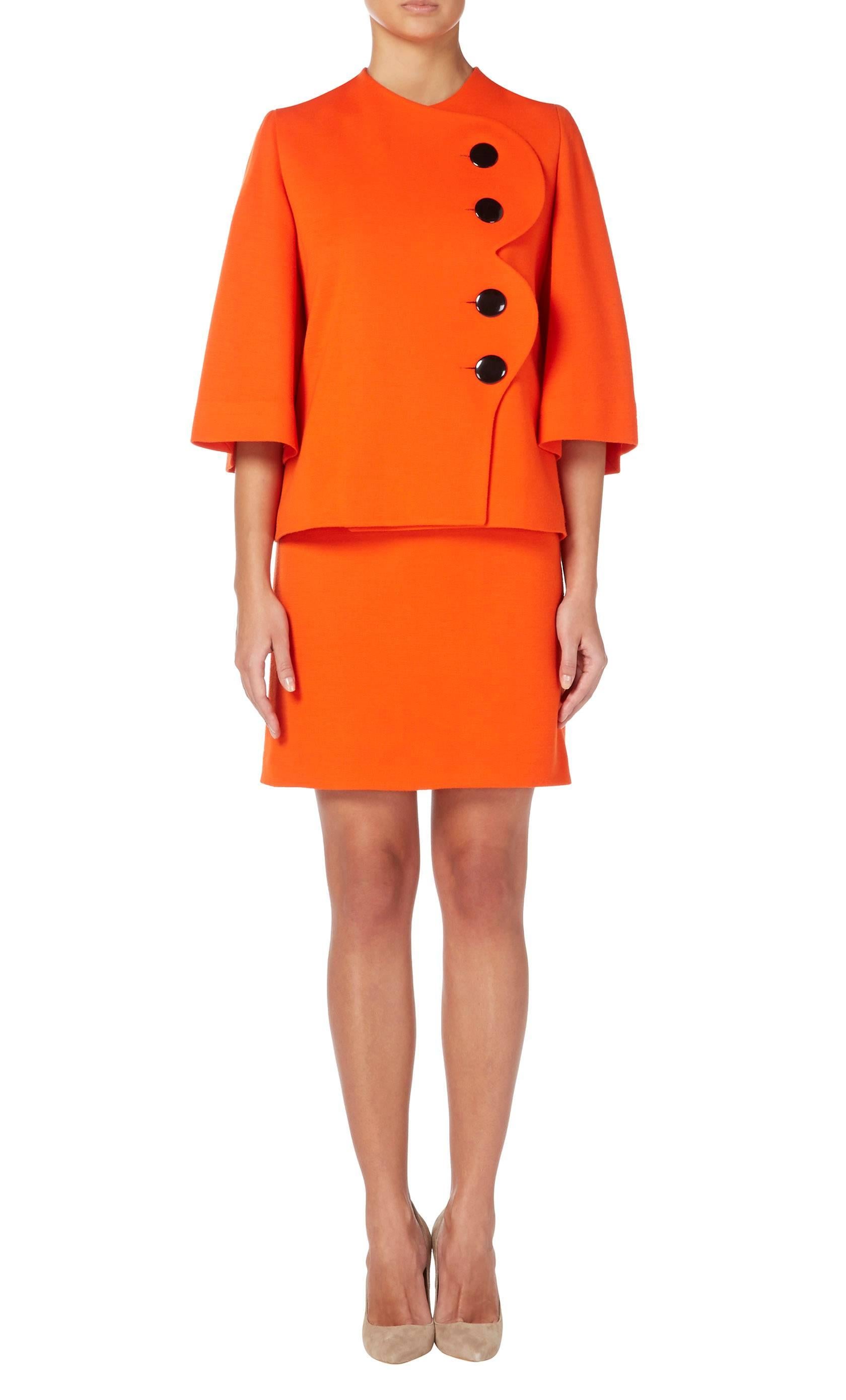 This bold Pierre Cardin skirt suit will make a colourful choice for the office or a daytime event. Constructed in vibrant orange wool, the jacket features split sleeves and a scalloped edge to the front, fastening with four overscale black buttons.