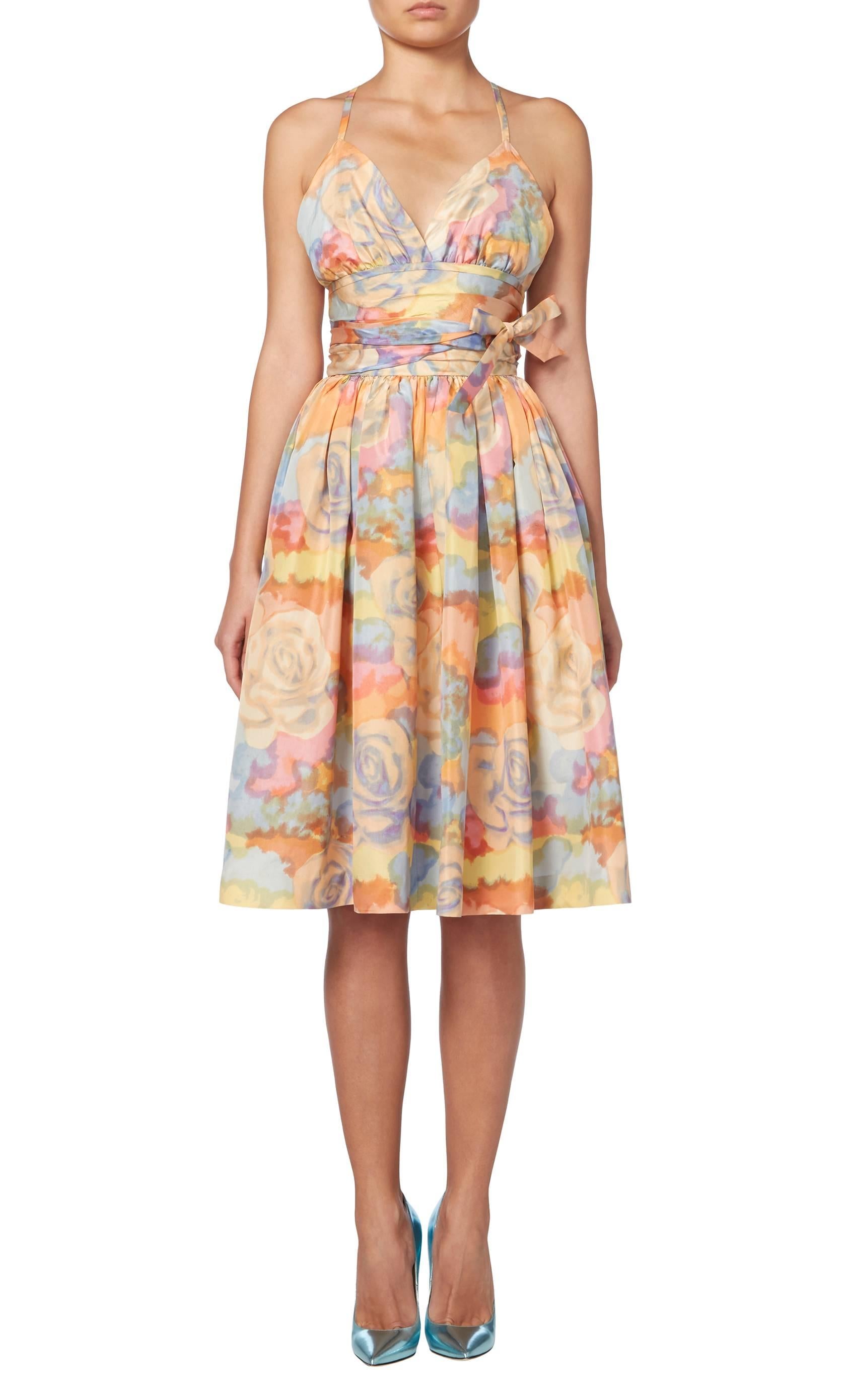 A simply stunning summer dress, this Norman Norell piece is perfect for garden parties and cocktails. Constructed in pastel coloured floral print silk, the dress features a crossover back and full skirt, while the waist is defined with a wide band