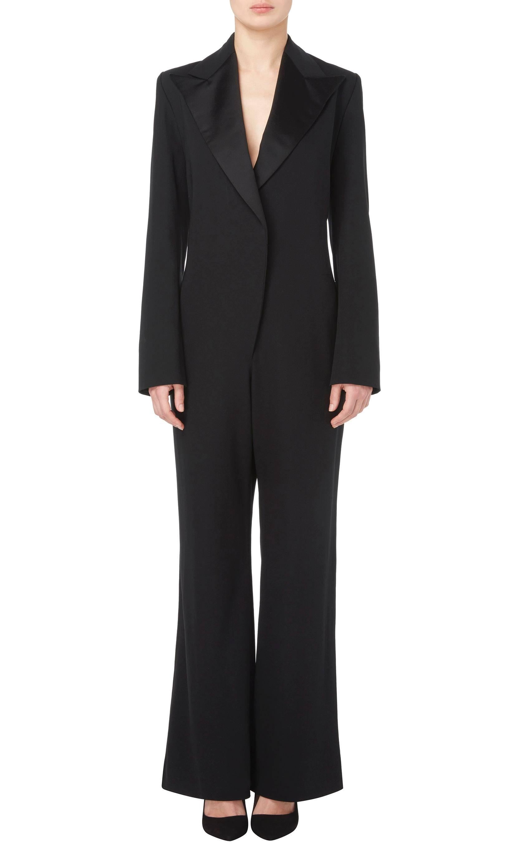 Constructed in black silk
Featuring a double lapel collar and padded shoulders
Press studs fastening to the front of the waist
Excellent condition with the original label, lining and fastenings
Professionally dry cleaned and