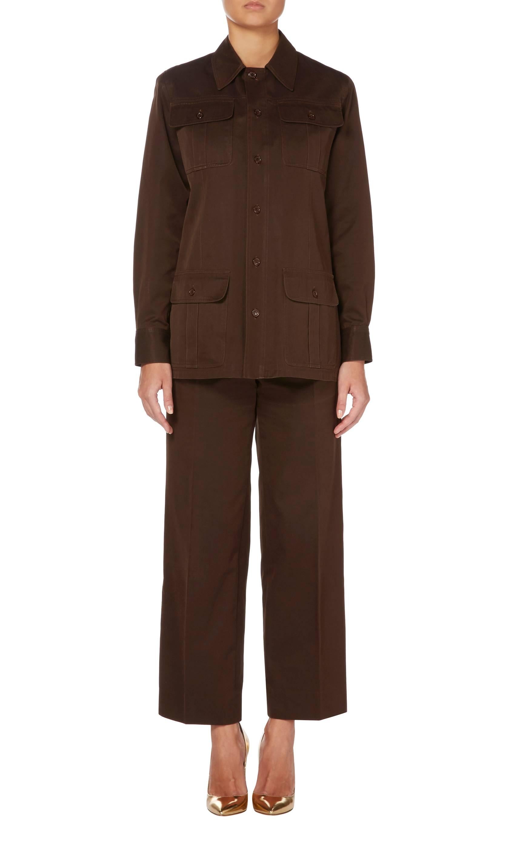 A fantastic example of the safari inspired designs that Yves Saint Laurent first debuted in 1968, this trouser suit is constructed in utilitarian style brown cotton. The long sleeved shirt features bellow pockets on the bust and hips, while the