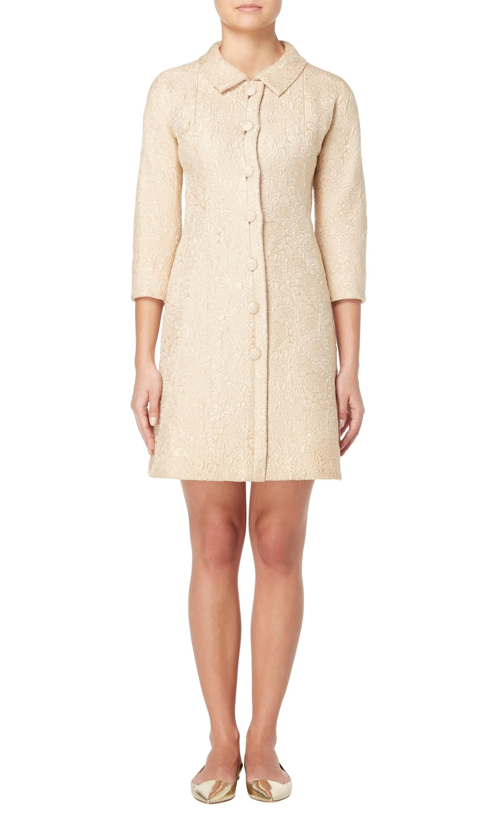 An incredible example of Balenciaga’s master tailoring, this haute couture coat dress is the height of chic. Constructed in beige silk brocatelle with a slight golden sheen, which shimmers in the light, the coat dress features seams that enhance the