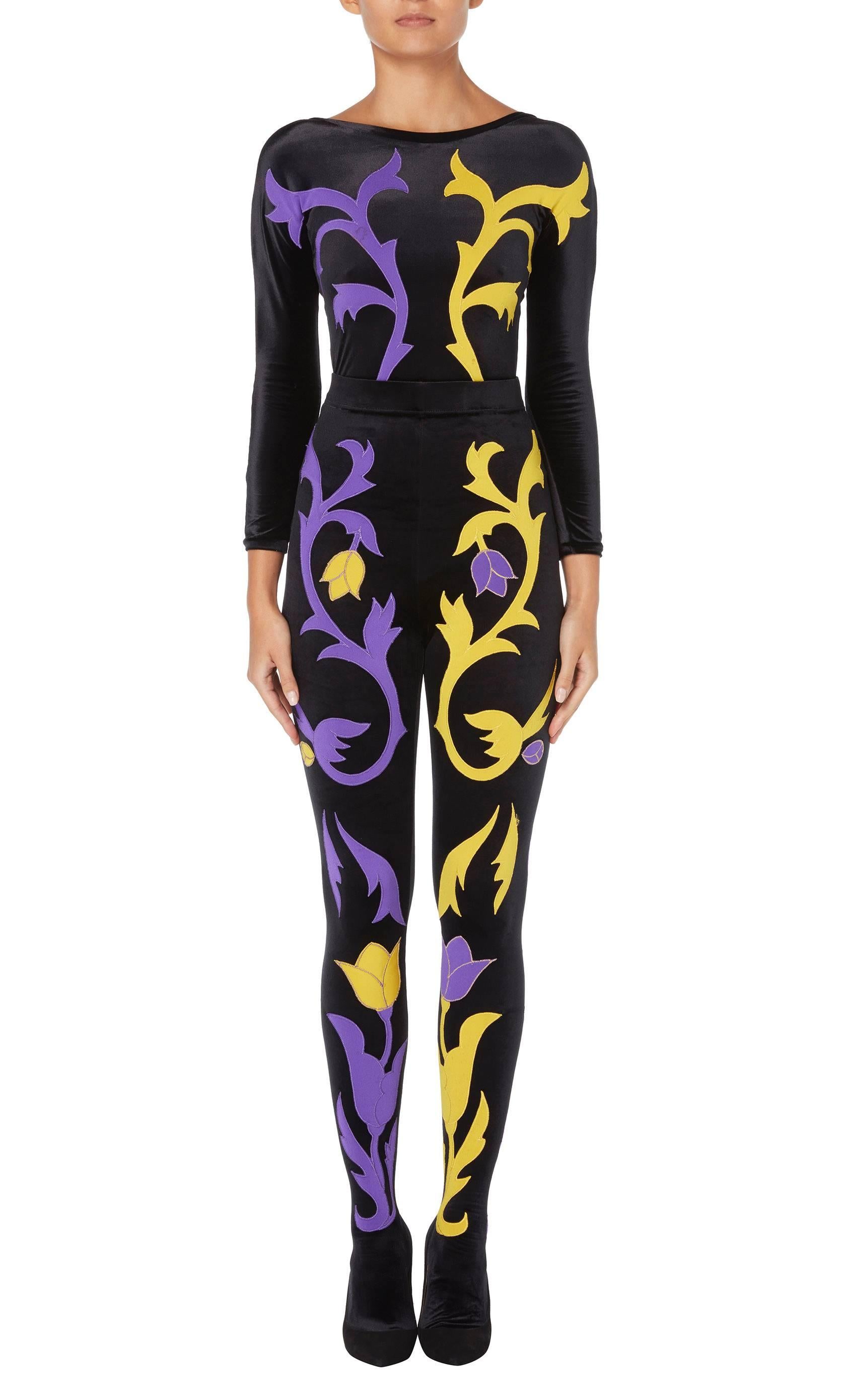 As seen on the Autumn/Winter 1991 runway, the identical Gianni Versace ensemble was modelled by Christie Turlington. Comprising of a long sleeved body and leggings, both pieces are constructed in stretchy black velour, and feature purple and yellow