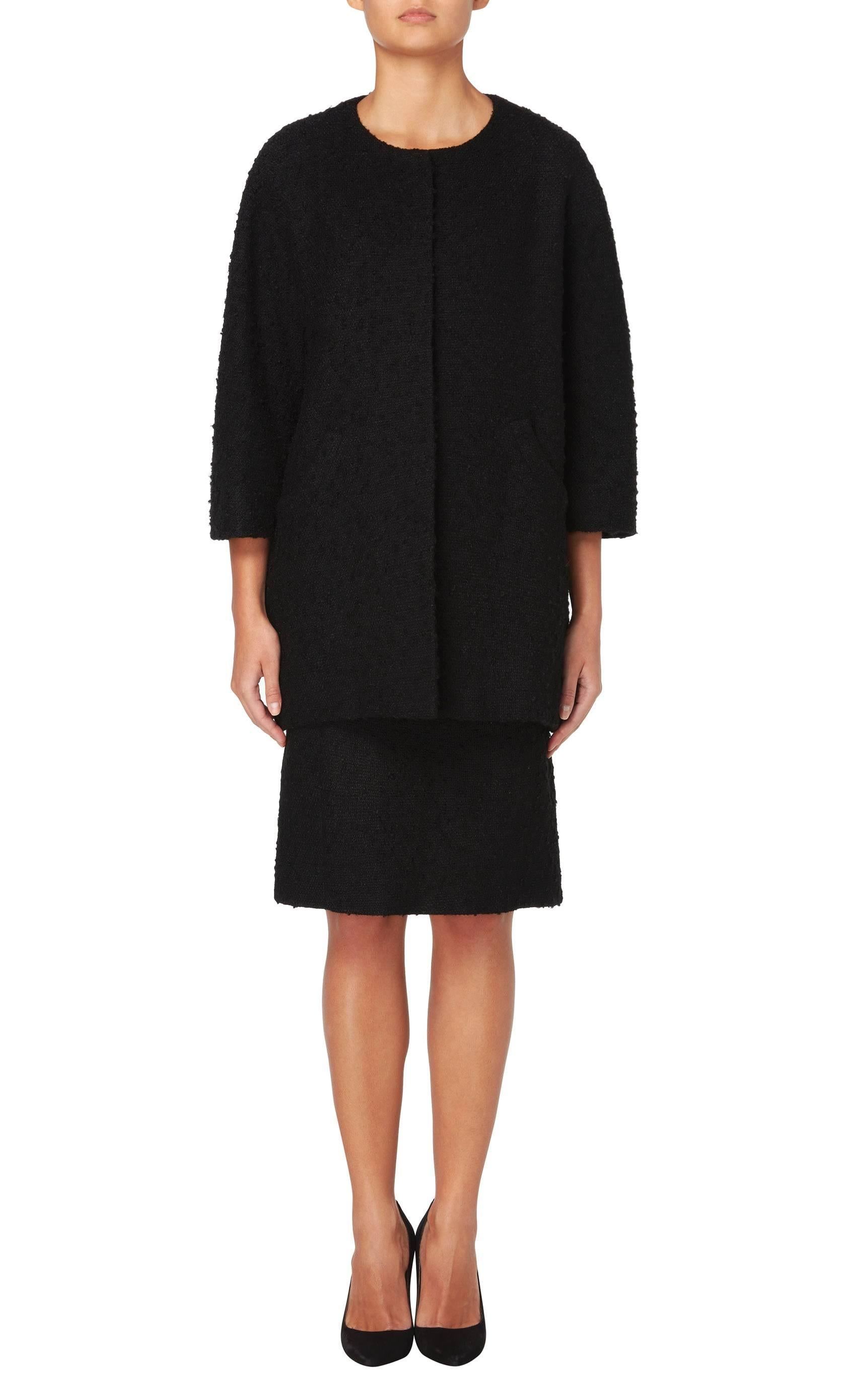 A superb example of Balenciaga’s classic tailoring, this haute couture skirt suit is constructed in black boucle wool and comprises of a jacket and skirt. The jacket features a round neckline and wide bracelet length sleeves, with Balenciaga’s