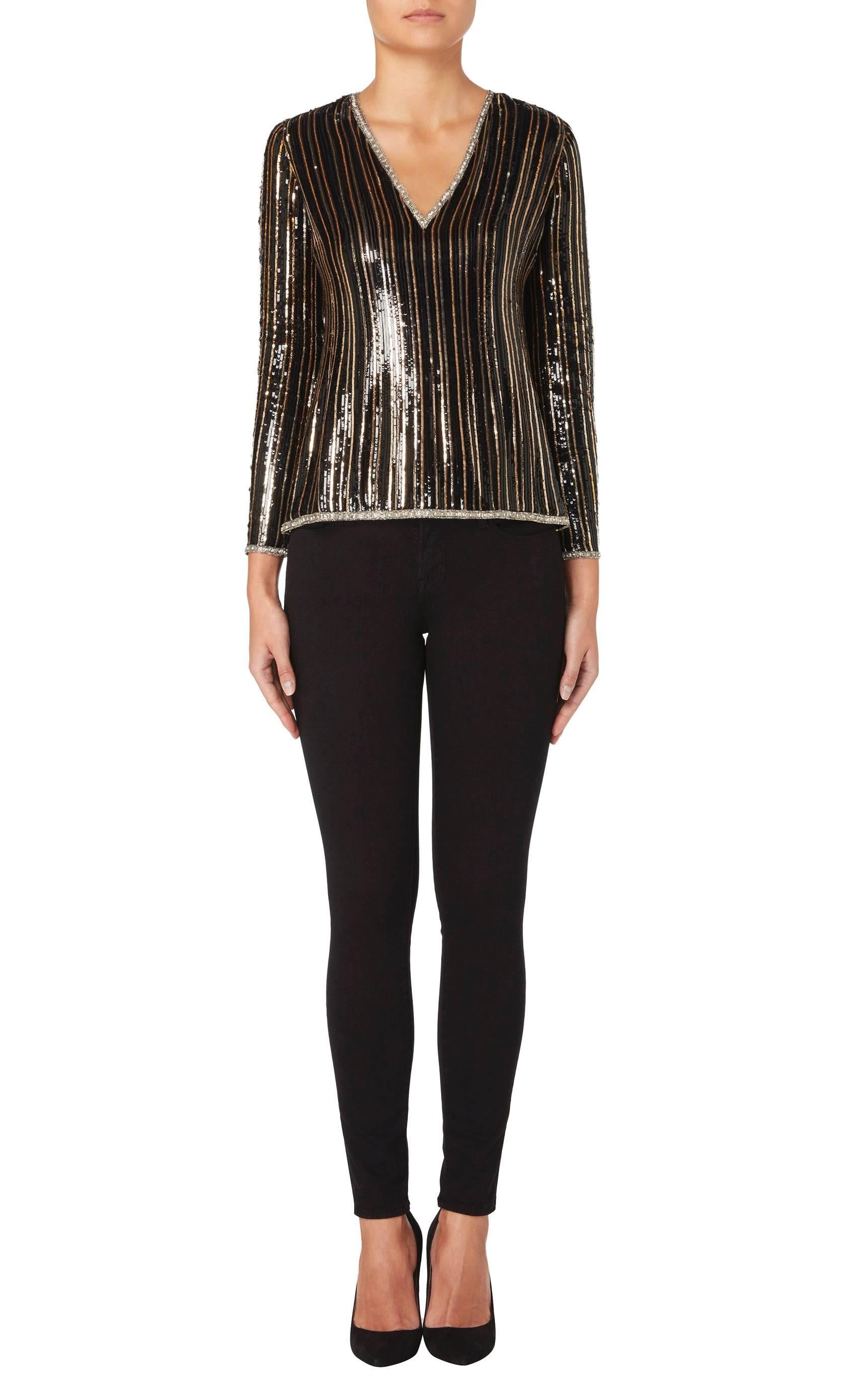 This shimmering Yves Saint Laurent haute couture top is made from black silk chiffon and embellished with scores of black, silver and gold sequins in vertical stripes, while crystal embellishment on the v-neckline, hem and cuffs adds to the