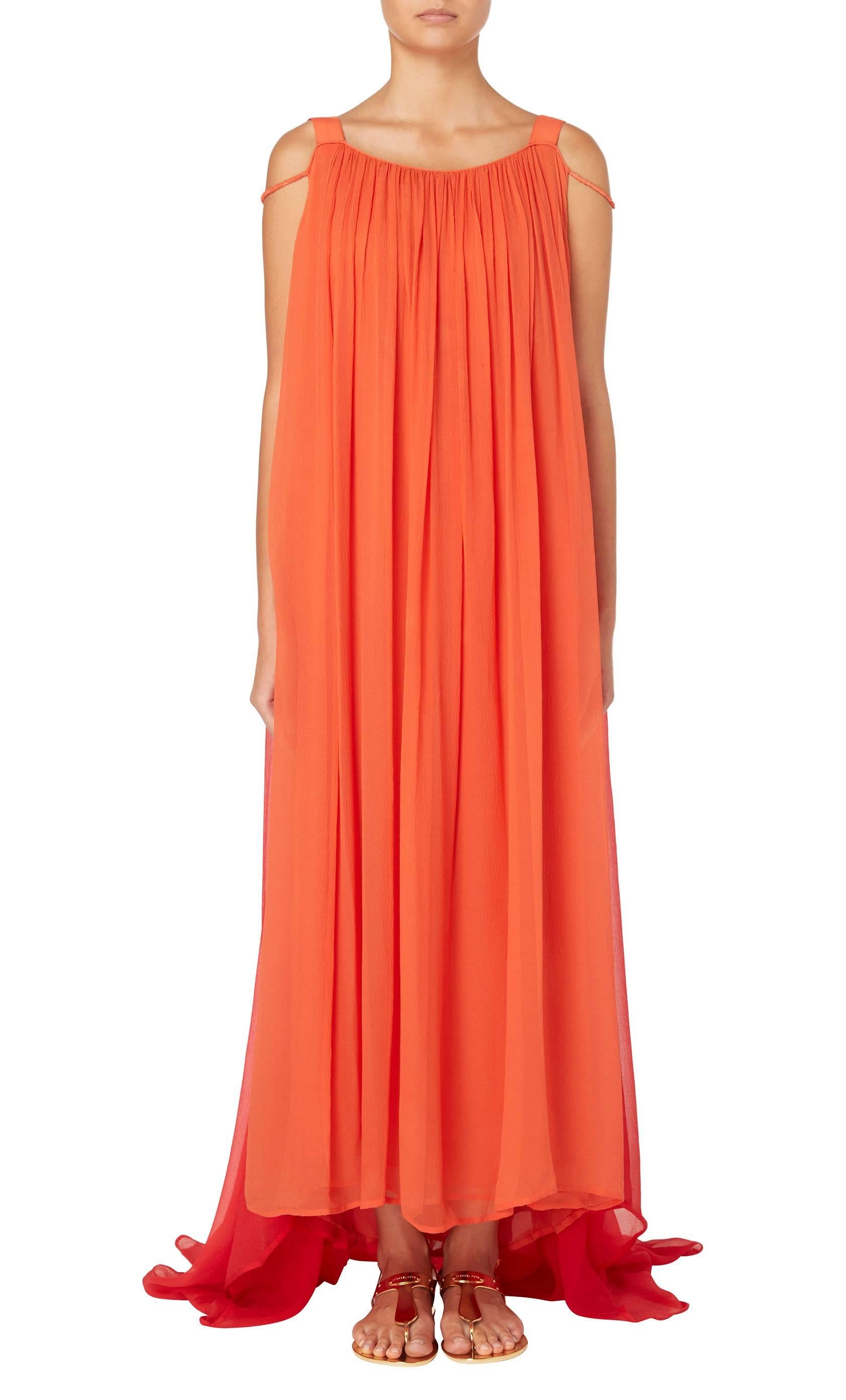 Constructed in layers of orange silk chiffon, this Yves Saint Laurent haute couture maxi dress features wide shoulder straps and a round neckline, plunging lower to the back. A layer of red chiffon creates a Watteau back, pooling into a train at the