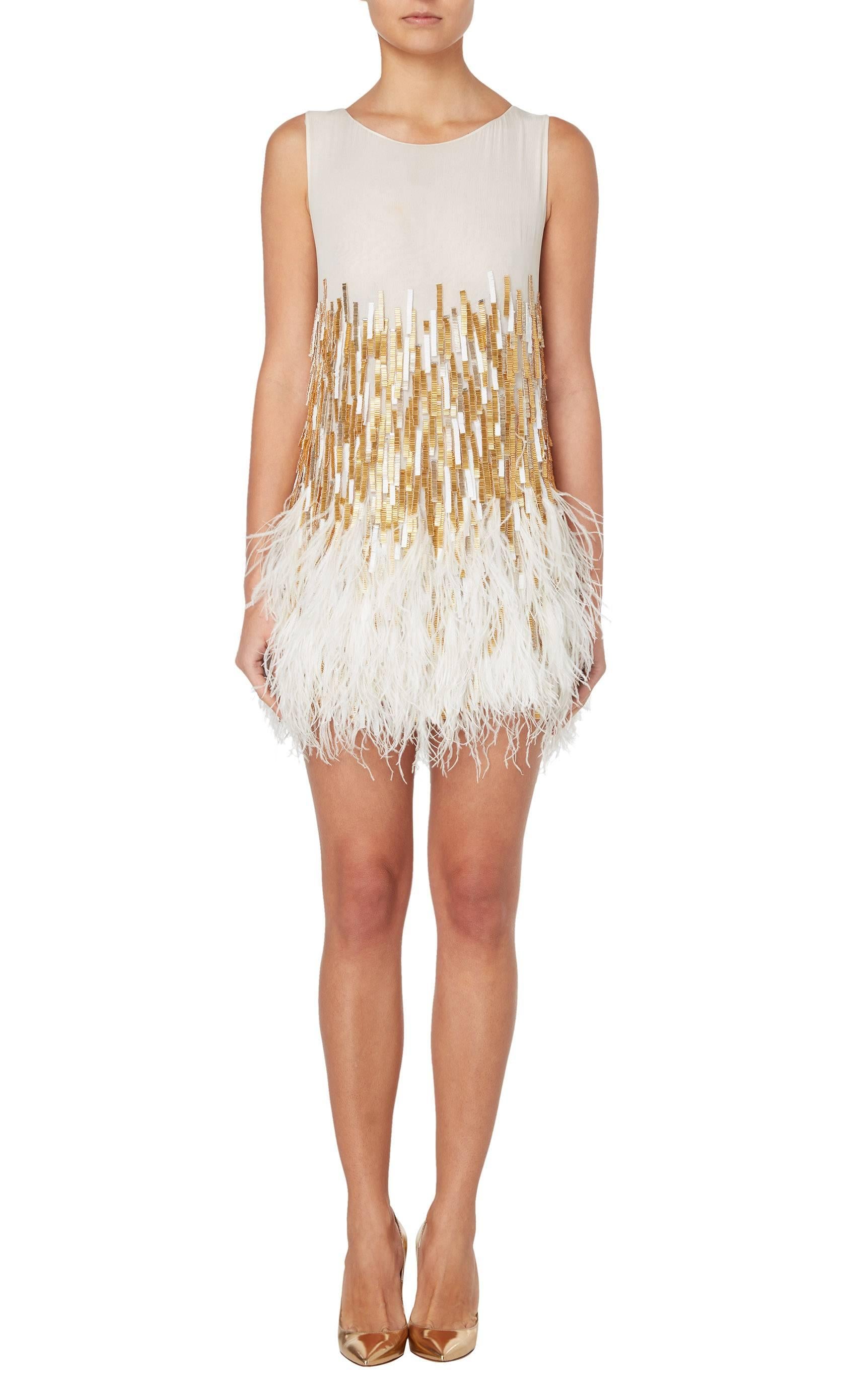 White sheer dress with gold an white beaded tassels and white ostrich feathers at hem.