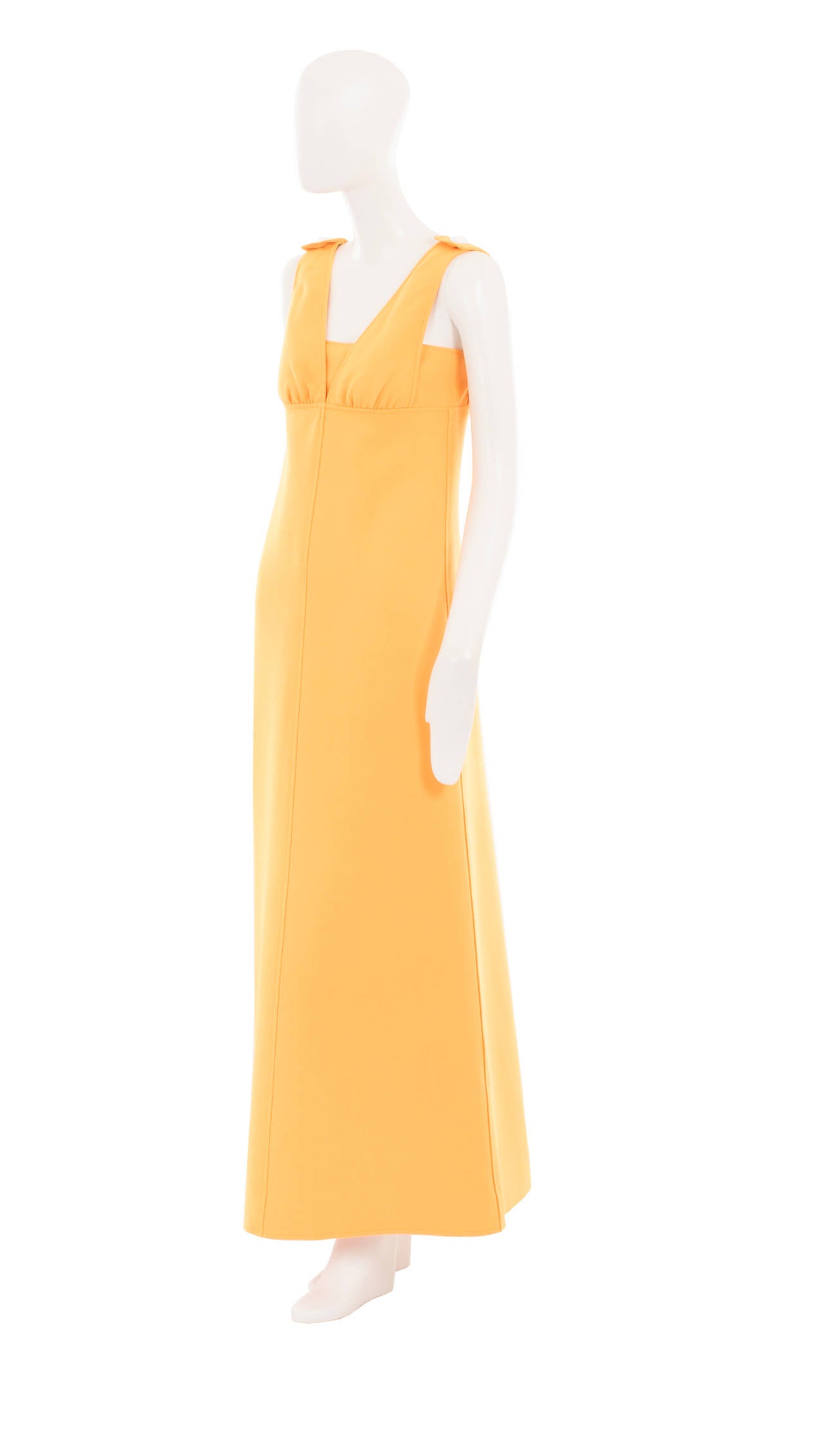 An amazing example of the modernist aesthetic that Courrèges was famous for, this saffron yellow maxi dress has a structured A-line silhouette. The dress features a v-neckline, with a seam running under the bust to create an empire line effect, and